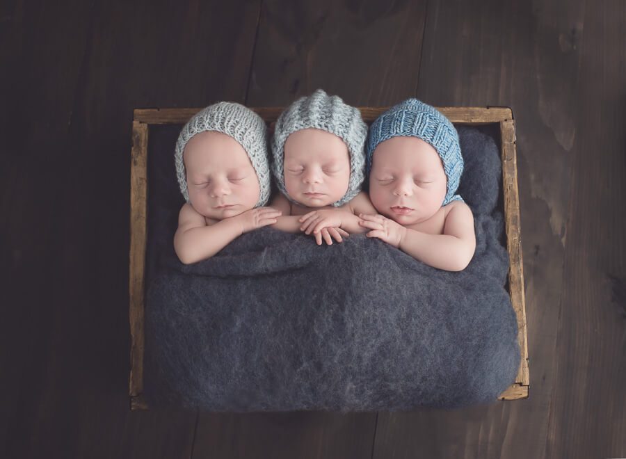 Melissa Hartigan Photography Connecticut Newborn Photographer-triplets babies in a crate wearing blue bonnets snuggling