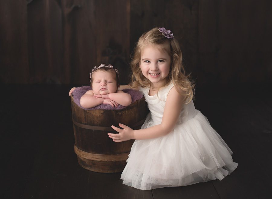 Melissa Hartigan Photography Connecticut Newborn Photographer baby and sister best big and little pretty dress smiling Siblings purple headbands