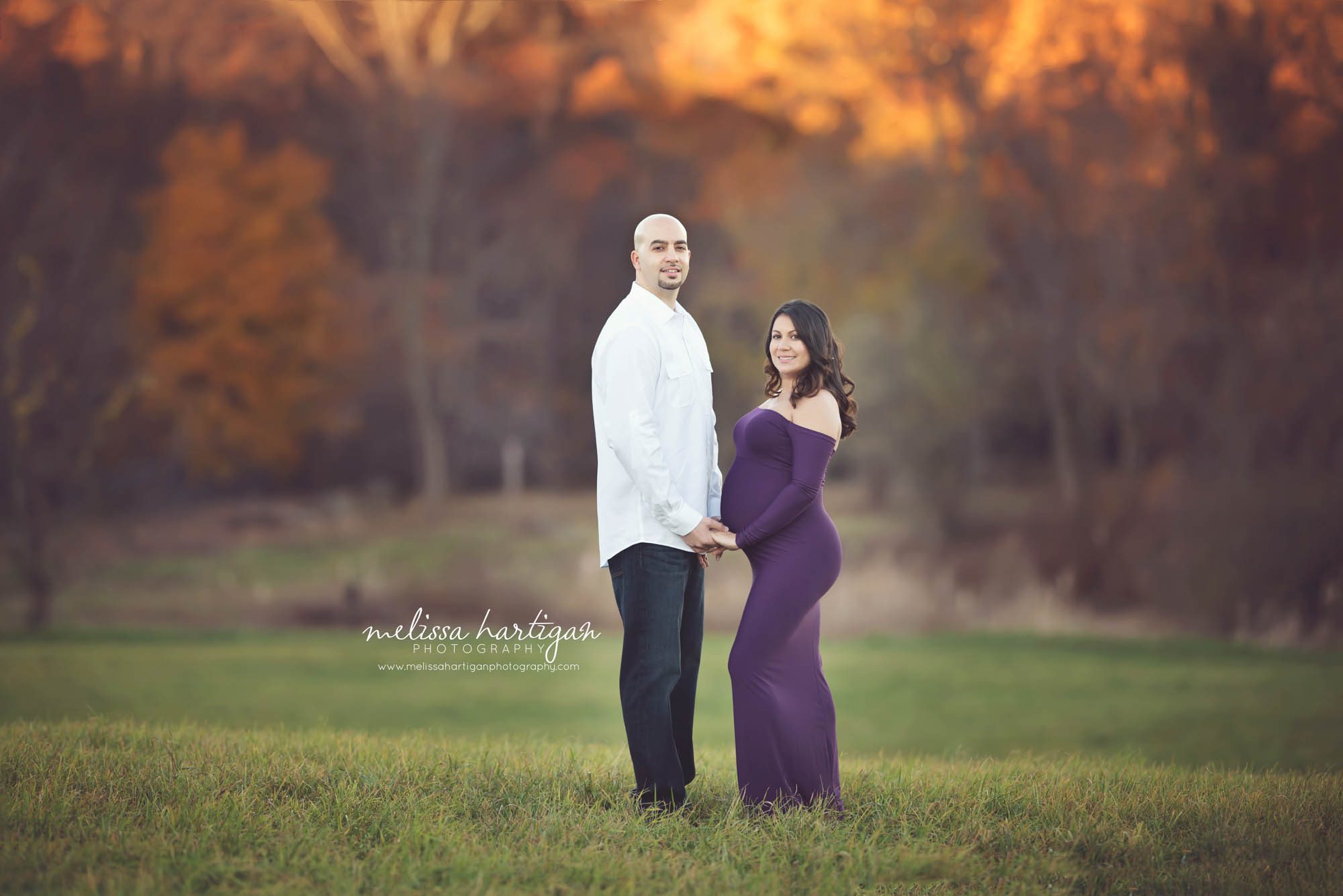 Melissa Hartigan Photography Connecticut Best Maternity Photographer in CT Coventry CT Middlefield CT Fairfield County Newborn and Maternity CT Photographer Maternity Photographer Parents-to-be outdoor session wearing purple maternity dress holding hands looking over shoulder