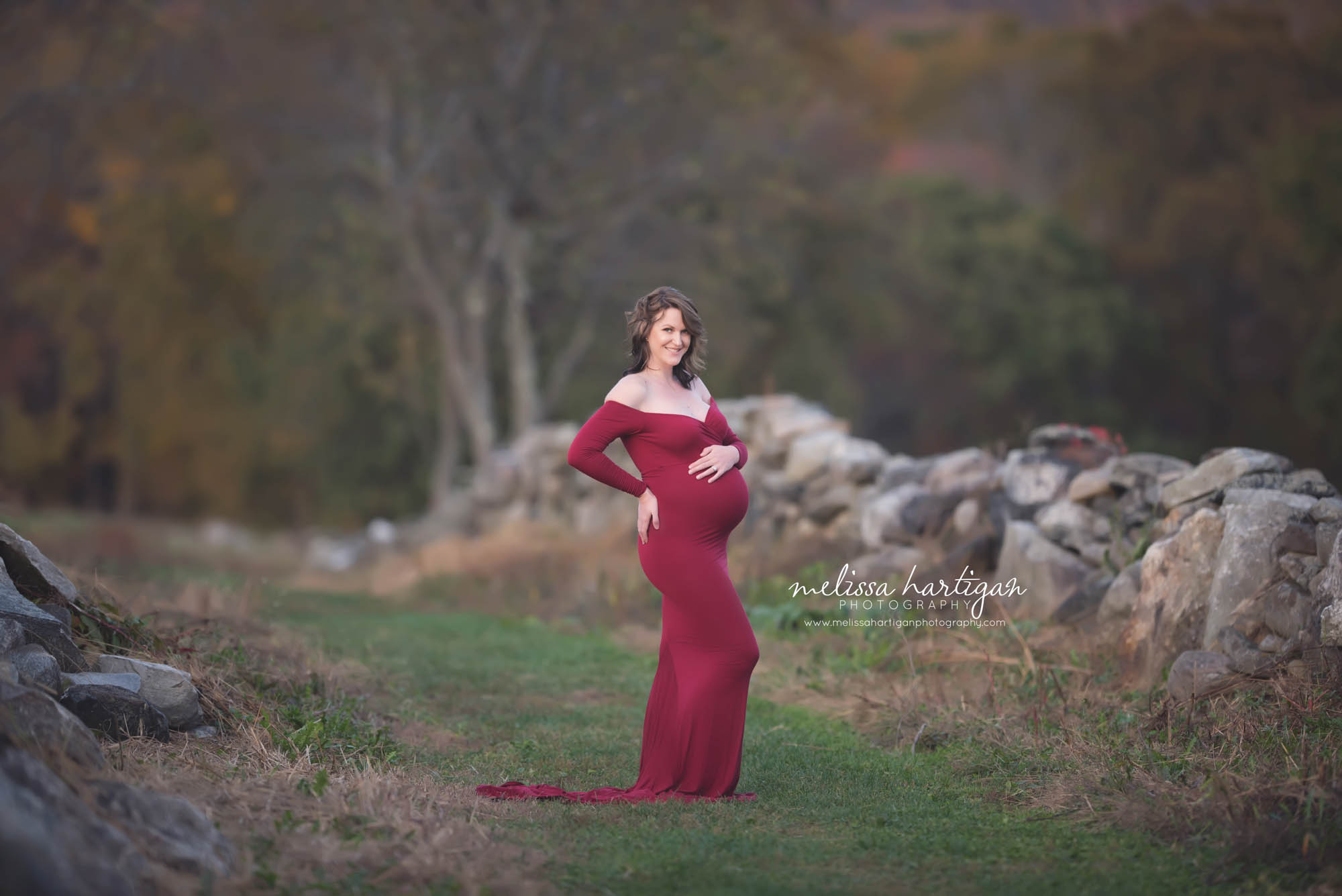 Melissa Hartigan Photography Connecticut Best Maternity Photographer in CT Coventry CT Middlefield CT baby Fairfield county Newborn and maternity CT photographer Maternity photographer Mommy-to-be outdoor session wearing red maternity dress holding belly standing in field by stone wall