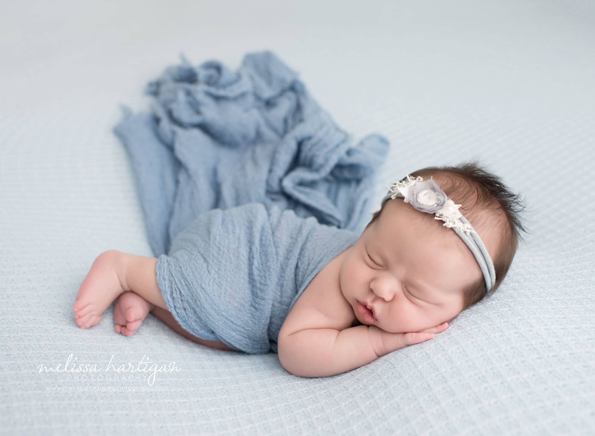 Melissa Hartigan Photography Connecticut Newborn Photographer Coventry Ct Middlefield CT baby Fairfield county Newborn and maternity photography Baby girl blue wrap with blue floral headband sleeping head on hands