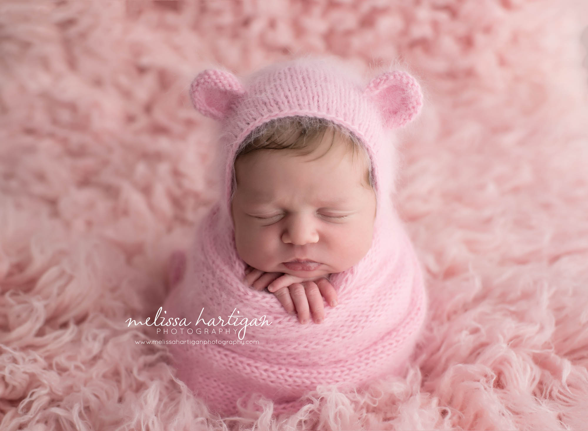 Melissa Hartigan Photography Connecticut Newborn Photographer Coventry Ct Middlefield CT baby Fairfield county Newborn and maternity CT photographer Baby girl pink wrap with pink earred knit hat with hands sticking out on pink flokati