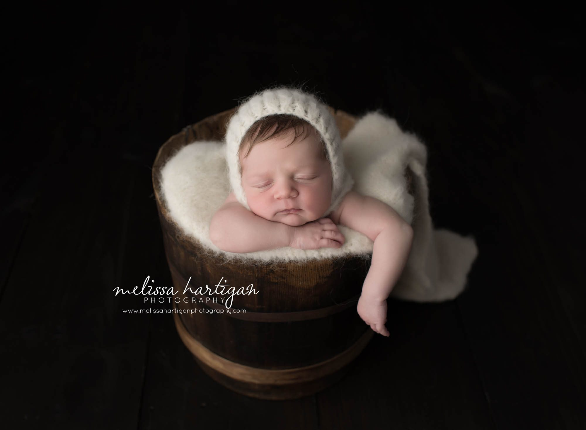Melissa Hartigan Photography Connecticut Newborn Photographer Coventry Ct Middlefield CT baby Fairfield county Newborn and maternity CT photographer Baby girl in wooden bucket with white knit hat and blanket with arm hanging out