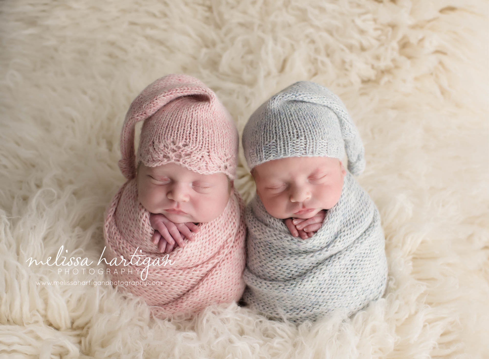 Melissa Hartigan Photography Connecticut Newborn Twin Photographer Coventry Ct Middlefield CT baby Fairfield county Newborn and maternity CT photographer Newborn twin photographer baby twins wearing pink and blue knit hats and wraps on white flokati