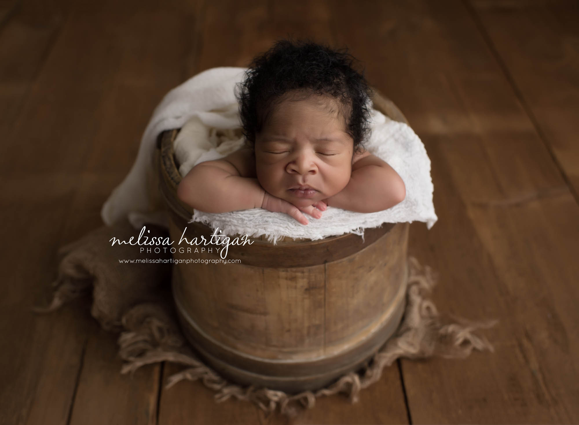 Melissa Hartigan Photography Connecticut Maternity and Newborn CT Photographer Coventry Ct Middlefield CT baby Fairfield county Newborn pose baby boy sleeping in antique wooden bucket with ivory blanket head on crossed arms