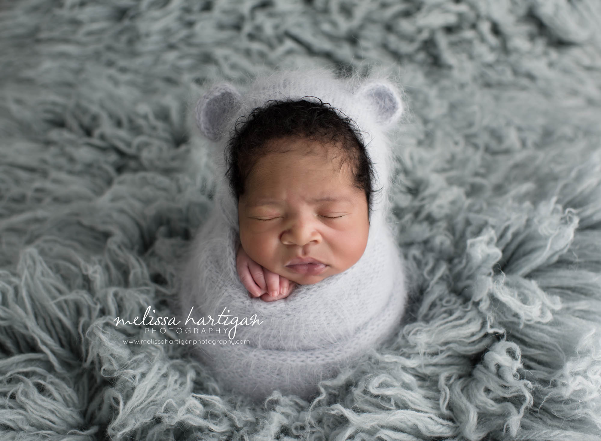 Melissa Hartigan Photography Connecticut Maternity and Newborn CT Photographer Coventry Ct Middlefield CT baby Fairfield county Newborn pose baby boy wrapped in blue with blue knitted hat with ears on a blue flokati