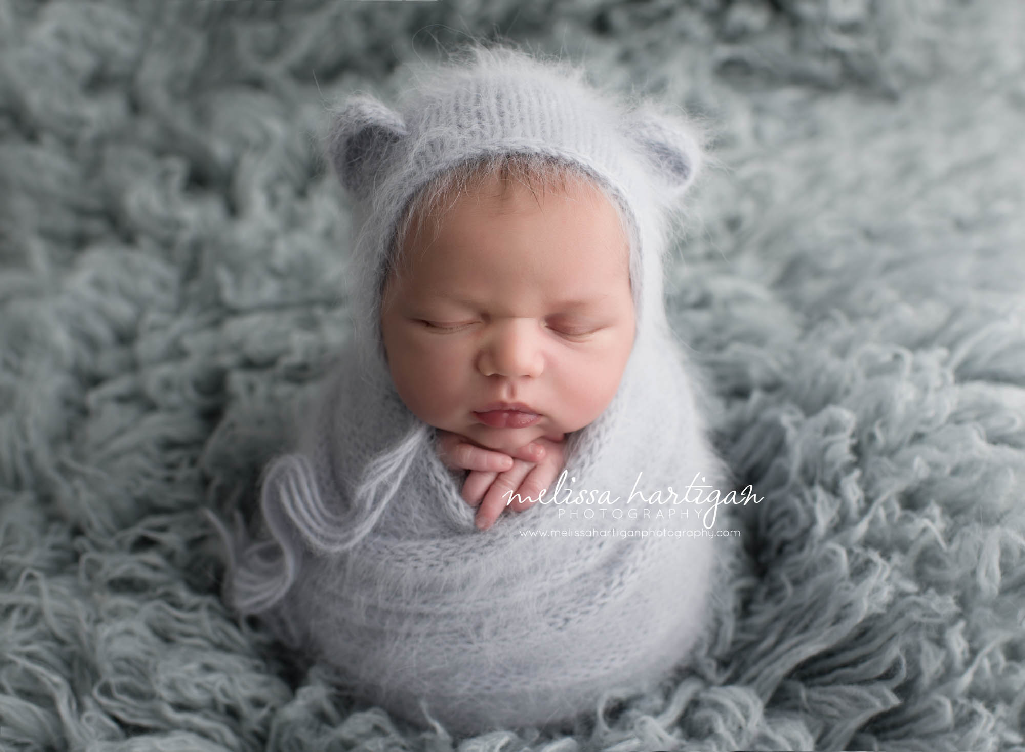 Melissa Hartigan Photography Coventry CT Simply Swaddled Newborn Session baby boy wrapped in pale blue knit with matching earred hat on blue flokati