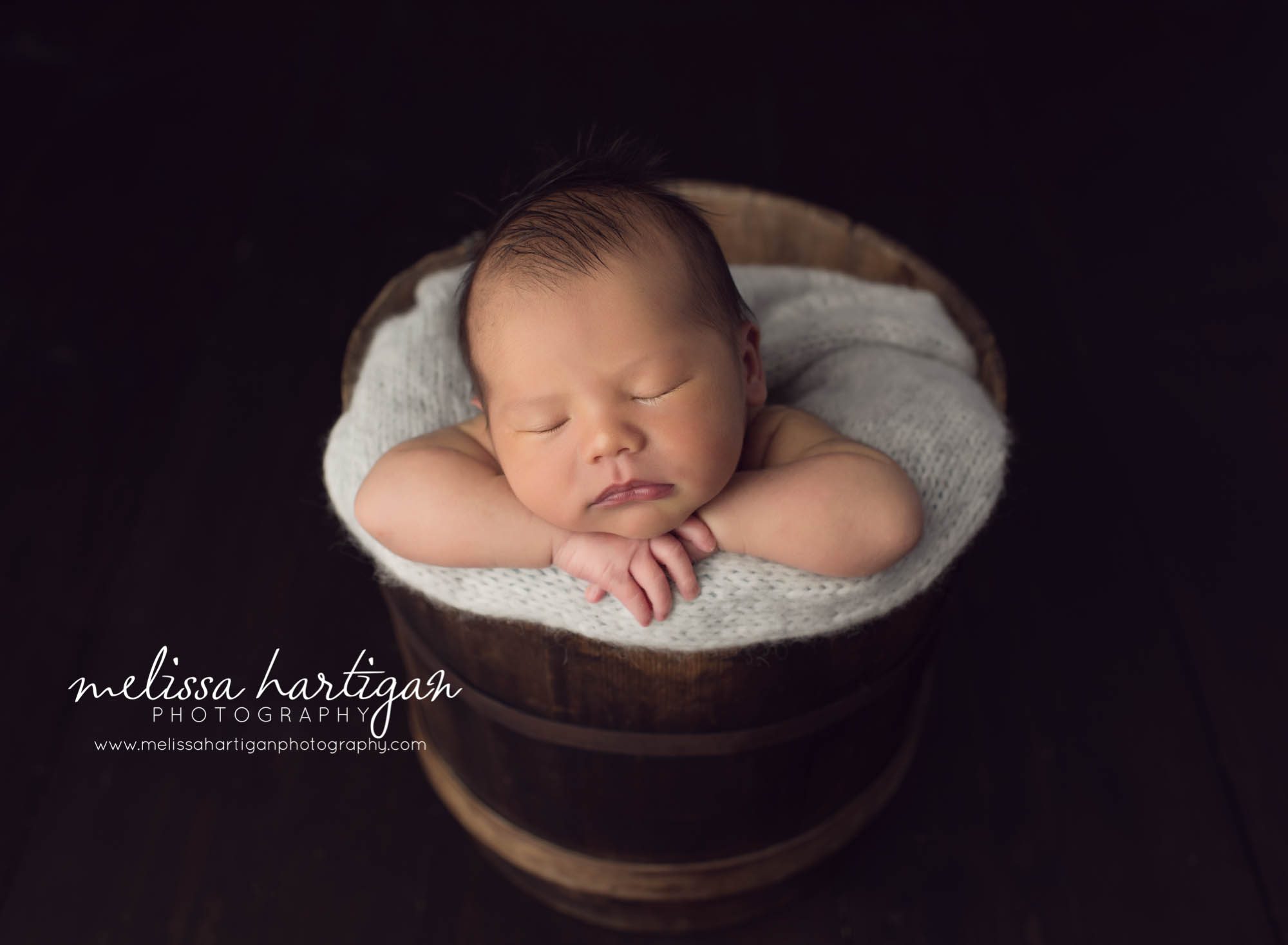 Melissa Hartigan Photography Maternity and Newborn Connecticut Photographer Lucas Newborn Session Baby boy in wooden bucket with light blue knit blanket sleeping on arms