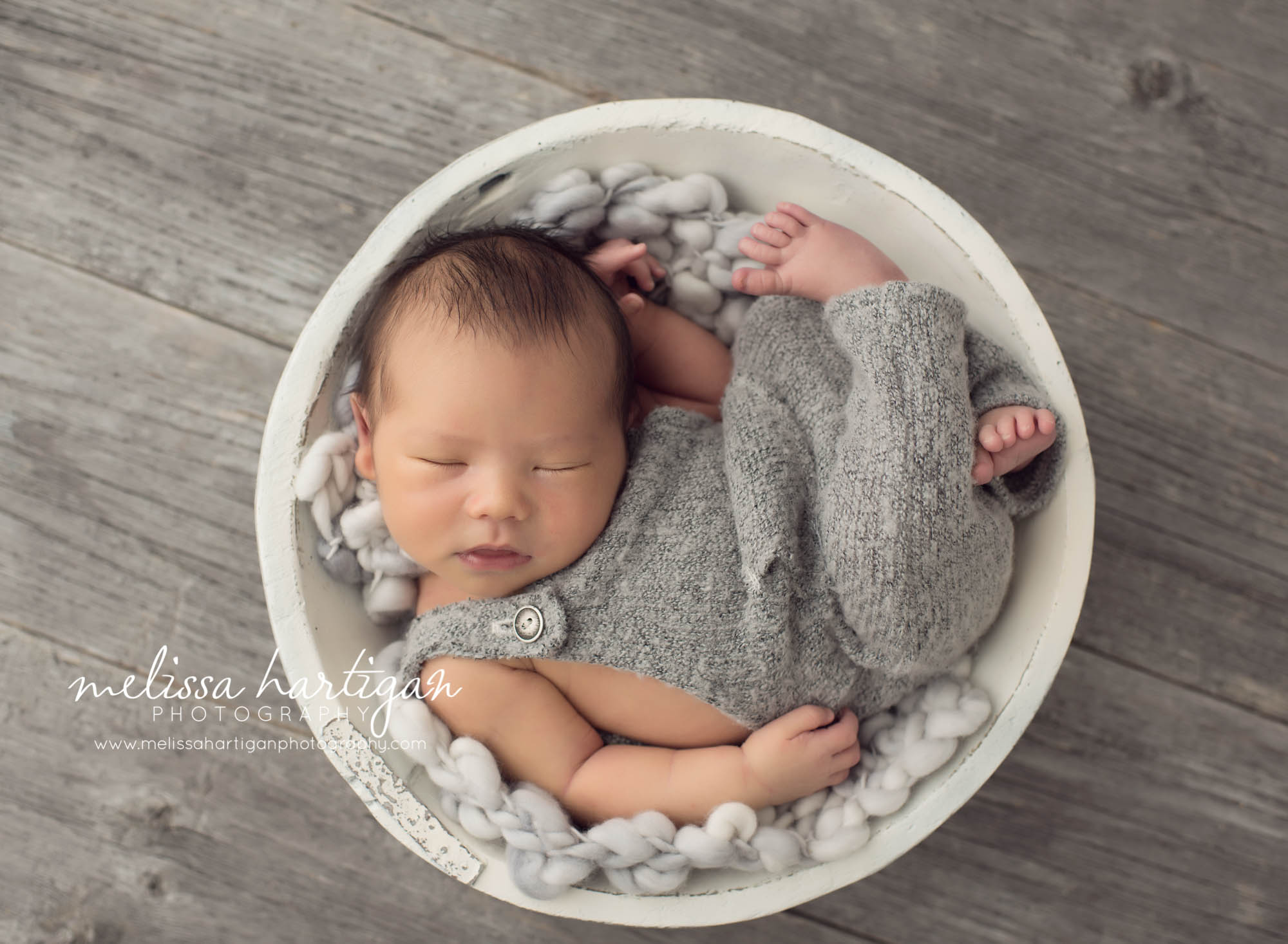 Melissa Hartigan Photography Maternity and Newborn Connecticut Photographer Lucas Newborn Session Baby boy sleeping in antiqued white bowl on light blue chunky knit blanket wearing gray knit overalls