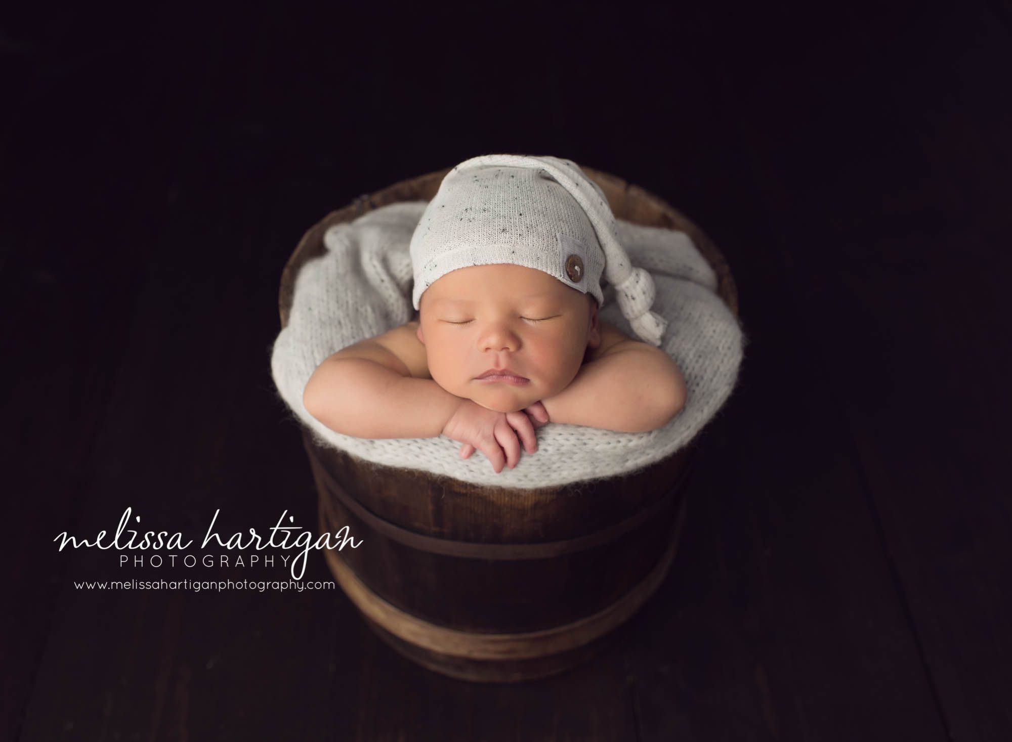 Melissa Hartigan Photography Maternity and Newborn Connecticut Photographer Lucas Newborn Session Baby boy sleeping in wooden bucket with knit blanket and knit hat