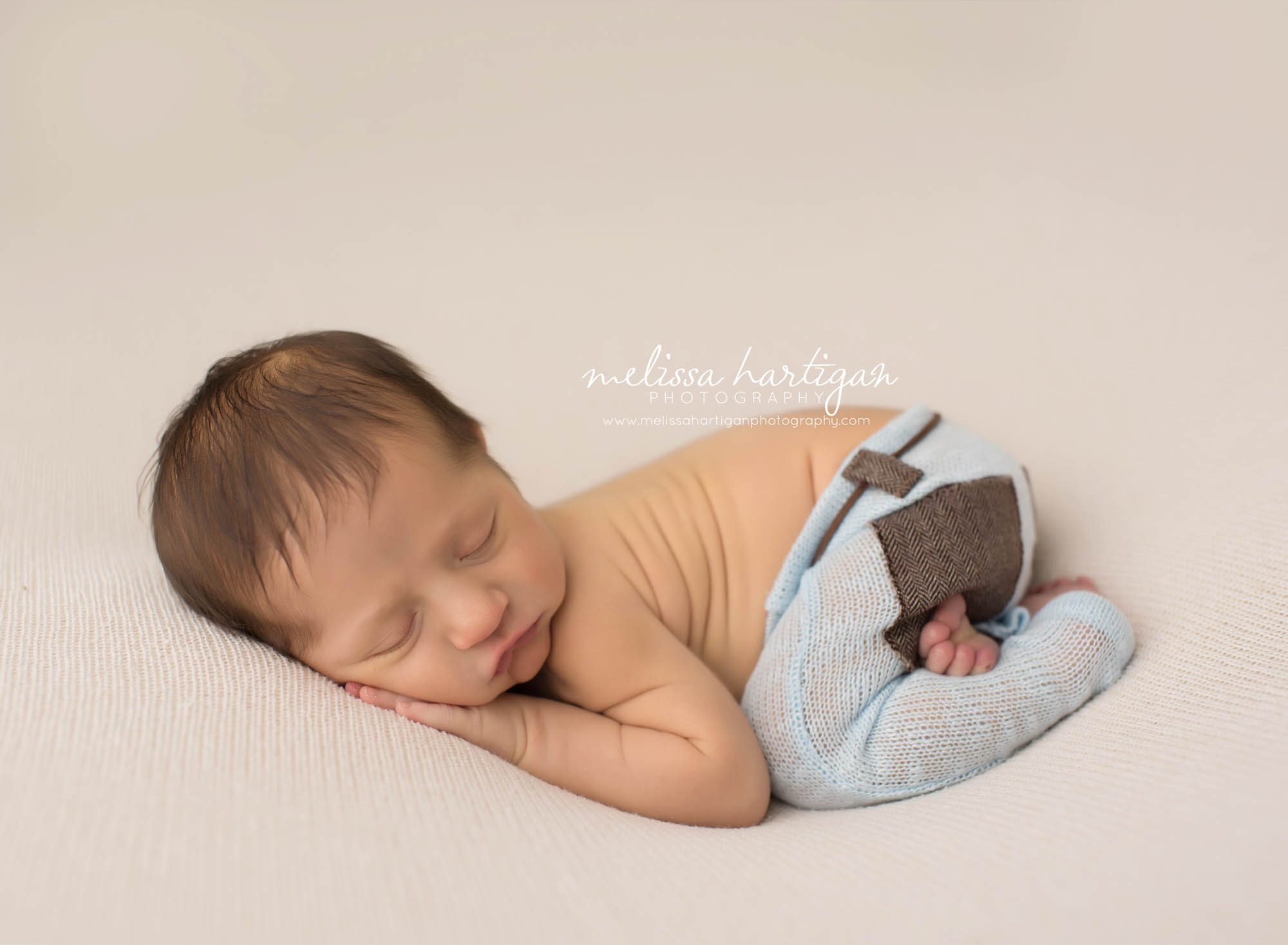 Melissa Hartigan Photography Maternity and Newborn Connecticut Photographer Brayden Mini Newborn Session Baby boy sleeping wearing light blue knit pants with foot tucked under tushy