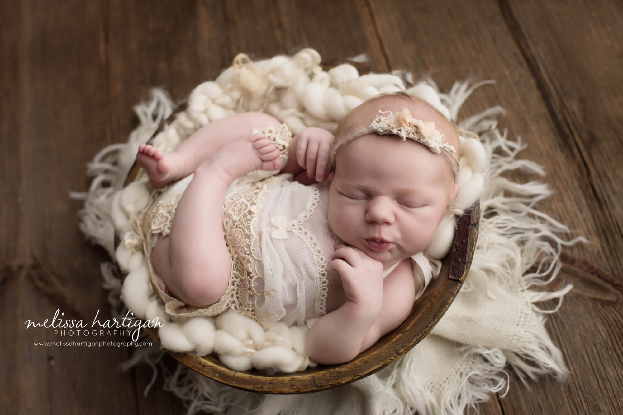 Melissa Hartigan Photography Connecticut Newborn Photographer in Coventry baby girl sleeping in wooden bowl wearing white lace romper making kissy lips