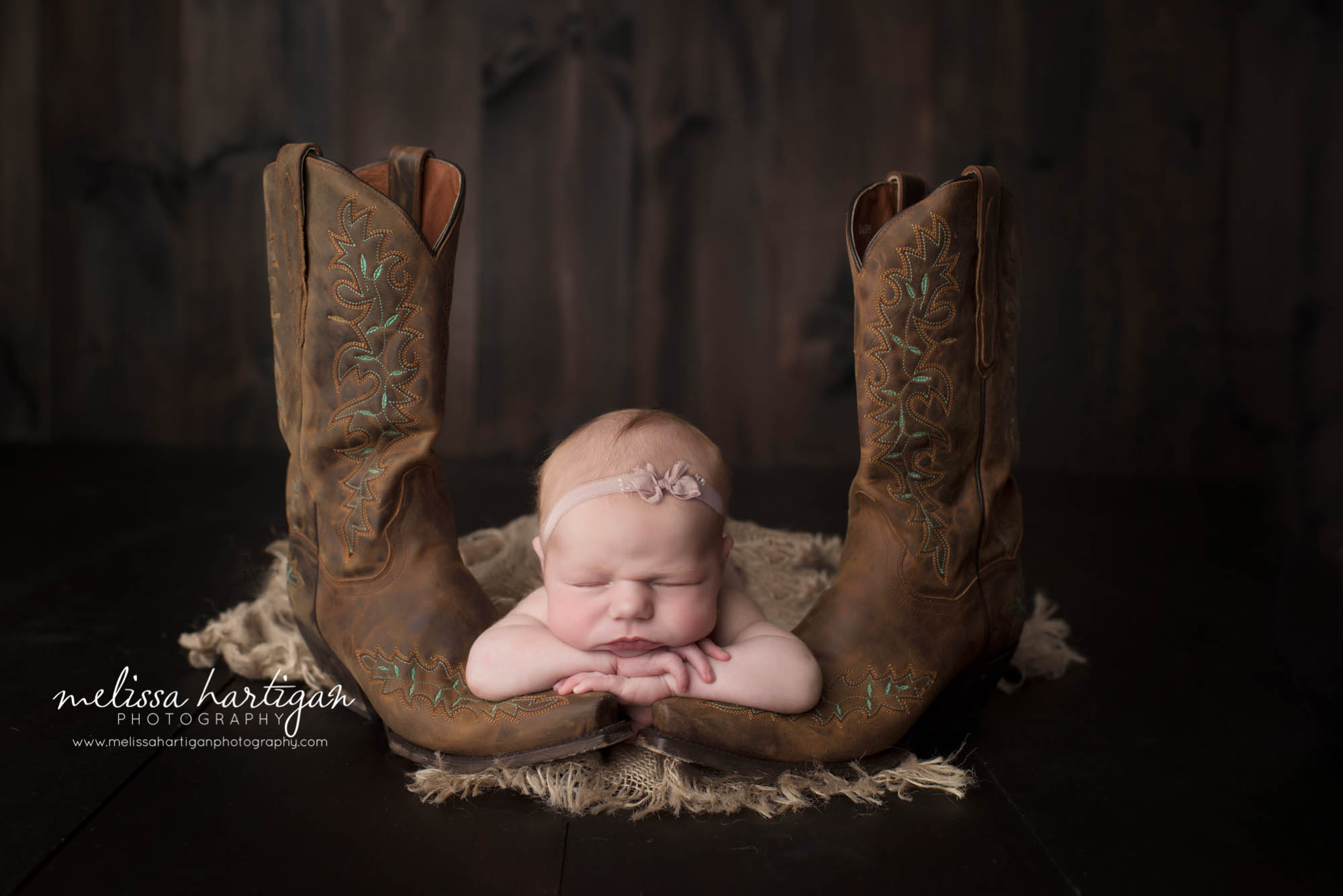 Melissa Hartigan Photography Connecticut Newborn Photographer in Coventry baby girl sleeping with head on crossed arms over mom's cowboy boots