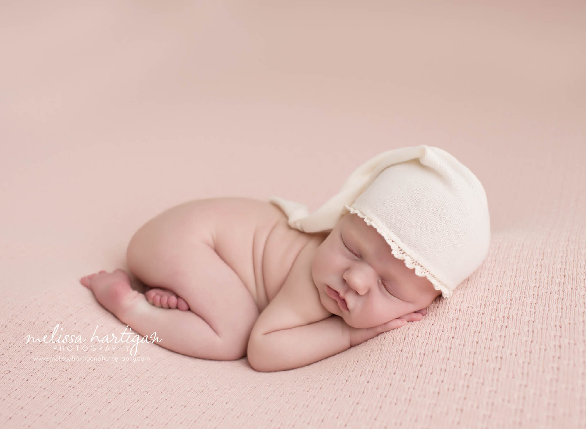 Melissa Hartigan Photography Connecticut Newborn Photographer in Coventry baby girl sleeping on pink blanket wearing a light pink knit hat