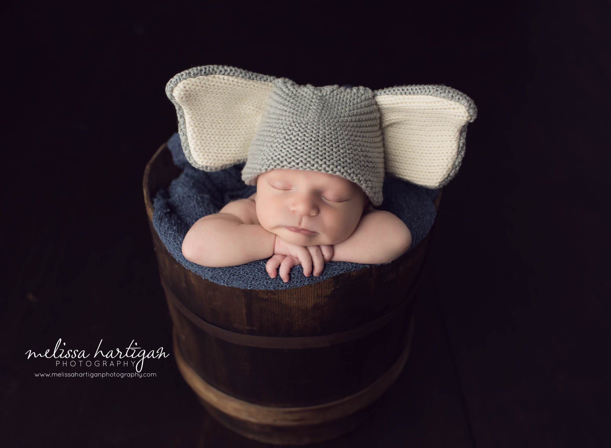 Melissa Hartigan Photography Newborn Photographer Connecticut baby boy sleeping in wooden bucket with blue throw wearing elephant knit hat