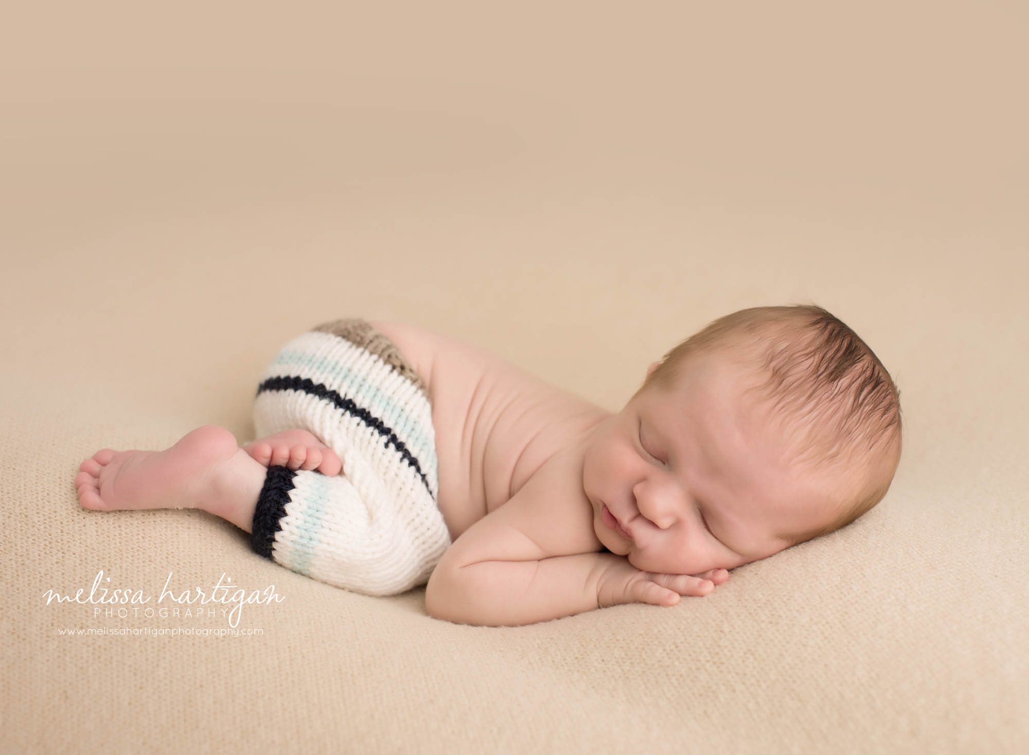 Melissa Hartigan Photography Newborn Photographer Connecticut baby boy wearing striped knit pants sleeping on light tan blanket