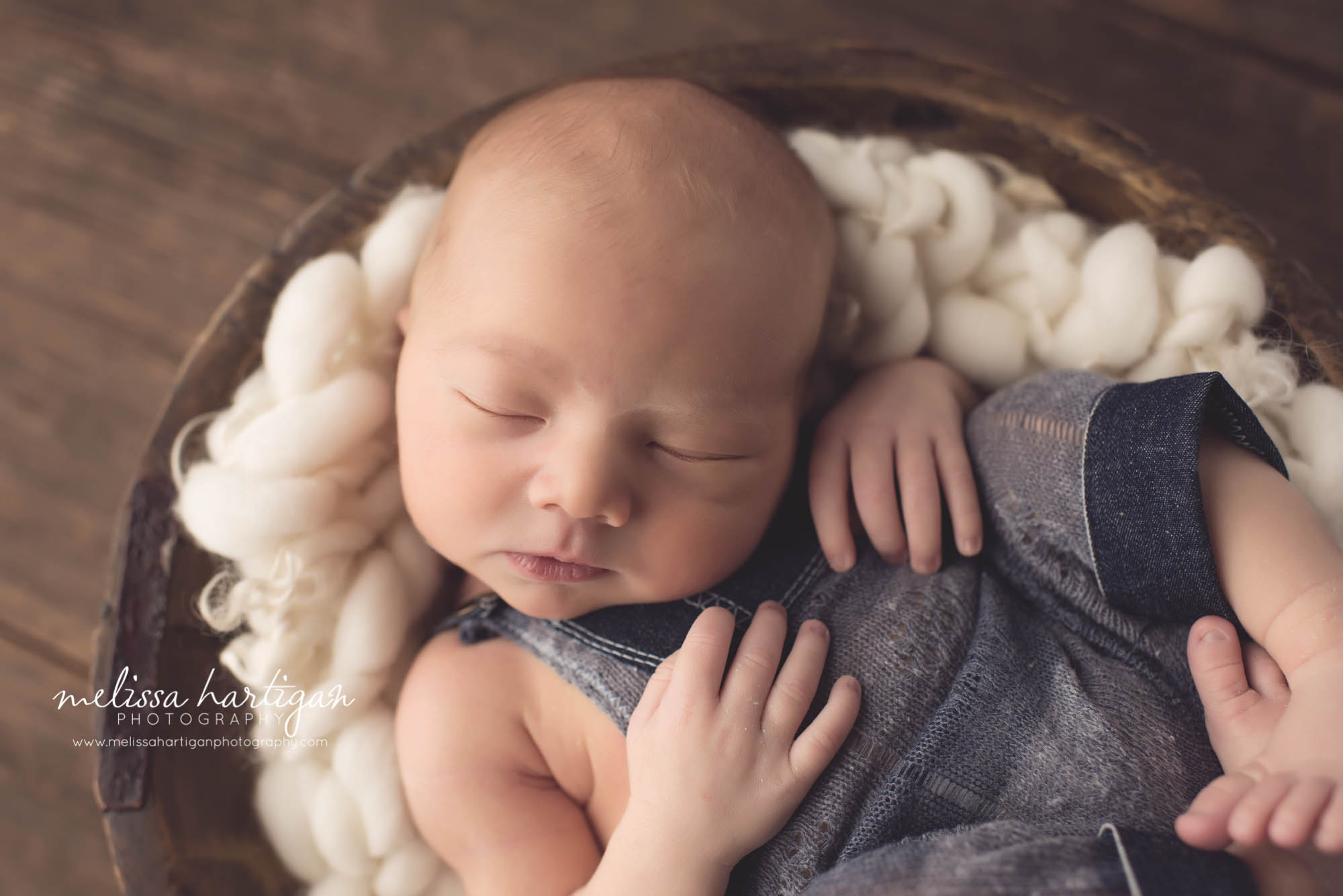 Melissa Hartigan Photography CT Newborn Photographer Braeden Newborn Session baby boy sleeping in wooden bowl with chunky knit cream blanket wearing blue knit overalls