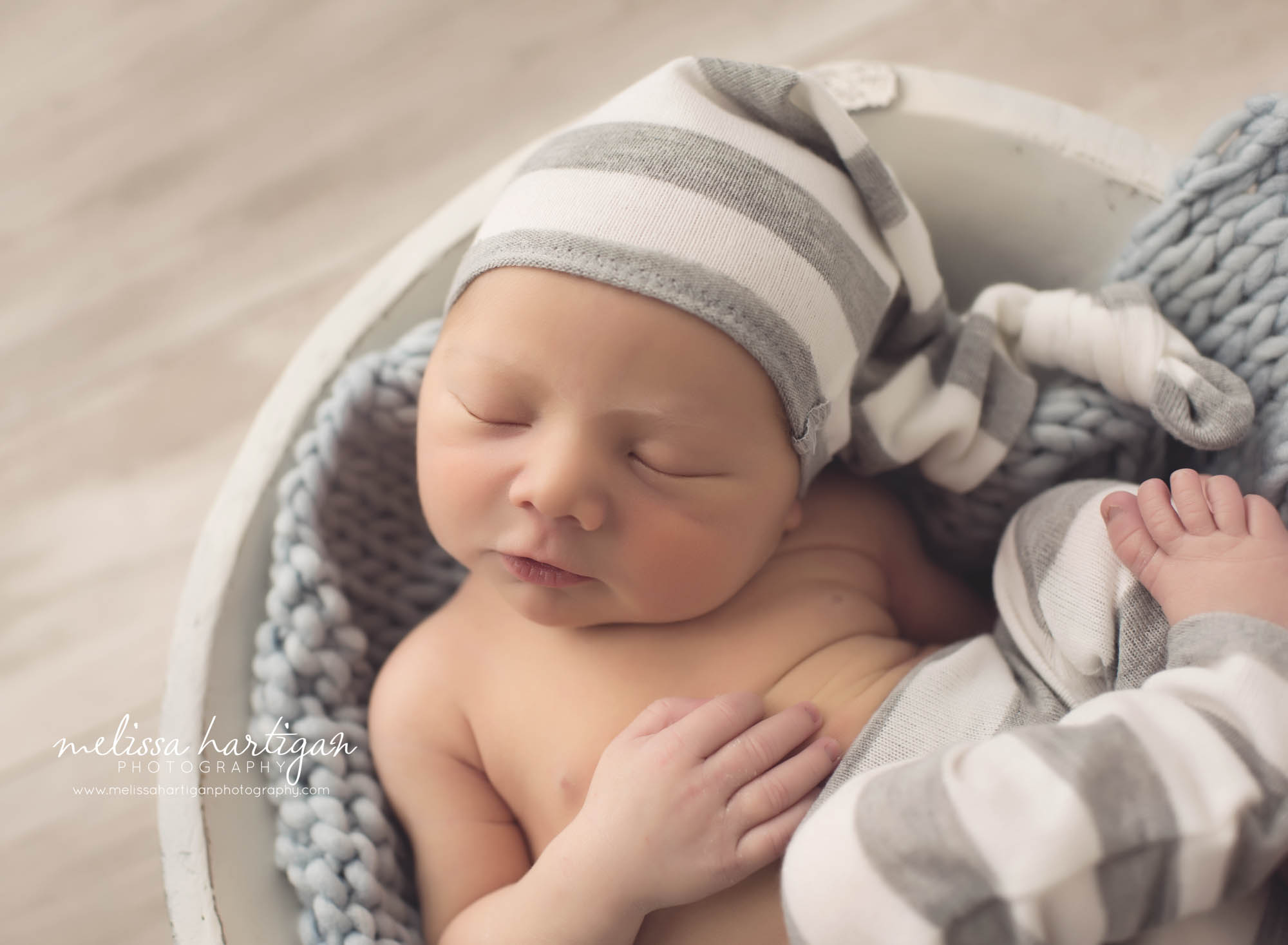 Melissa Hartigan Photography CT Newborn Photographer Braeden Newborn Session baby boy sleeping in white wooden bowl with gray blanket wearing striped knit gray and white hat and pants