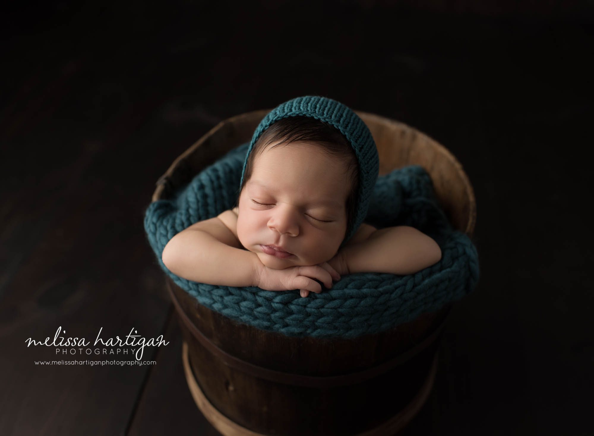 Melissa Hartigan Photography CT Newborn Photographer East Hartford baby boy sleeping in wooden bucket with blue knit blanket and hat