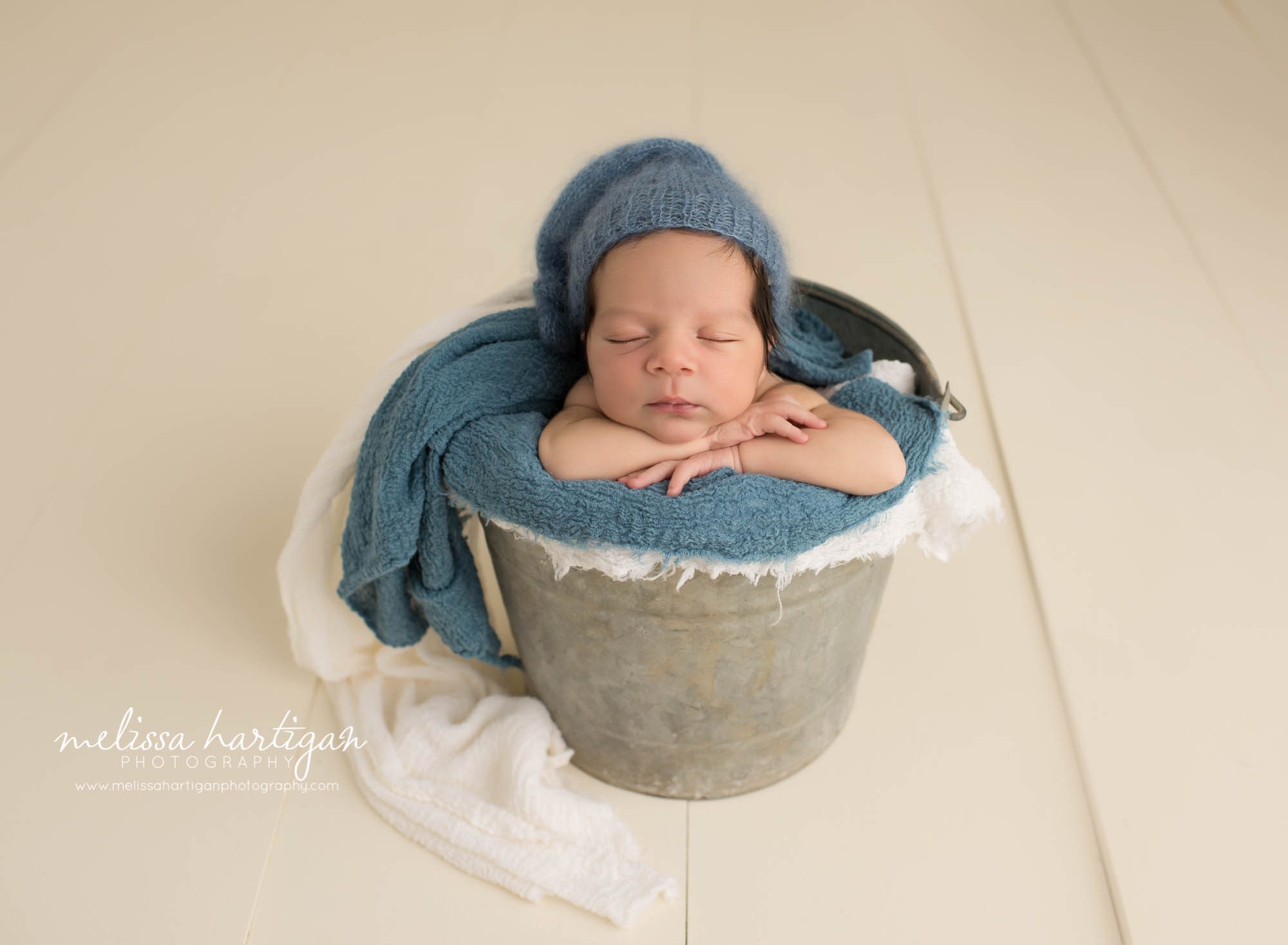 Melissa Hartigan Photography CT Newborn Photographer East Hartford baby boy sleeping in metal bucket with blue knit blanket and knit hat
