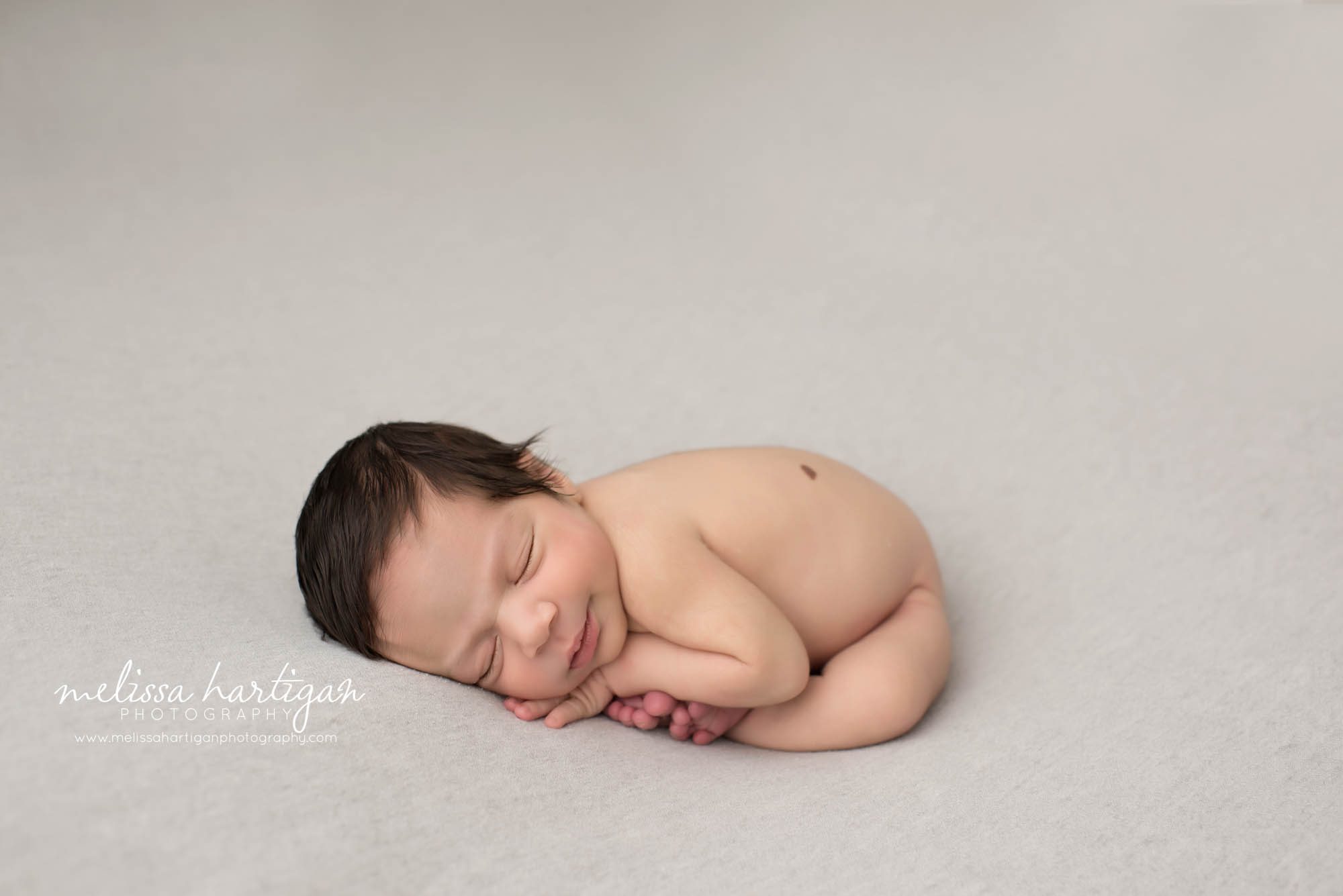 Melissa Hartigan Photography CT Newborn Photographer East Hartford baby boy sleeping on blue blanket smiling curled up