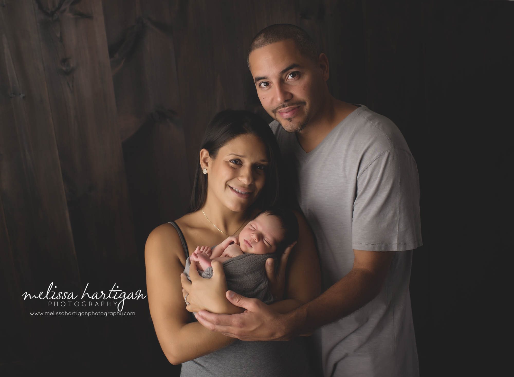 Melissa Hartigan Photography CT Newborn Photographer East Hartford baby boy sleeping wrapped in gray held by mother and father