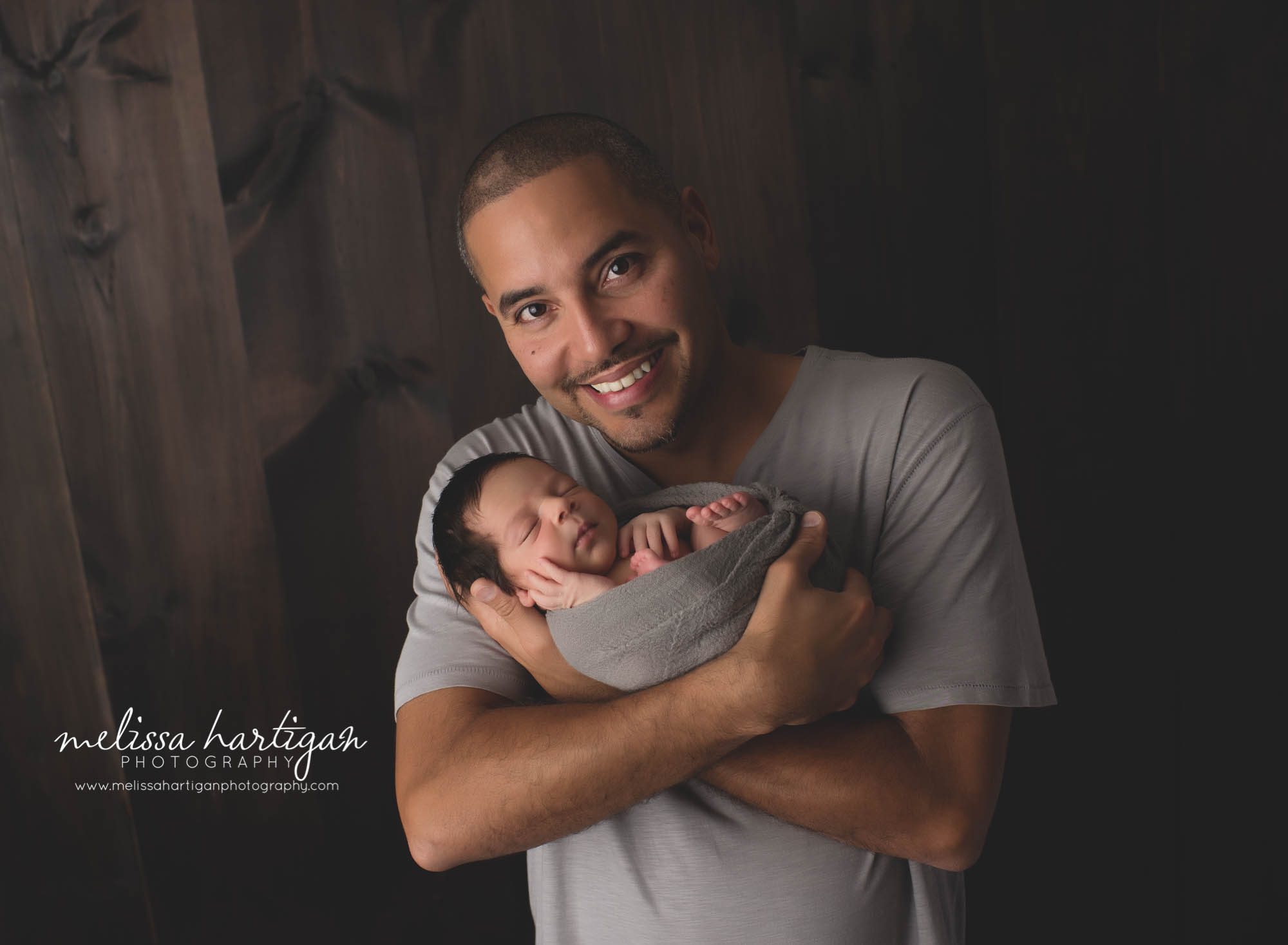 Melissa Hartigan Photography CT Newborn Photographer East Hartford baby boy sleeping wrapped in gray with father holding him