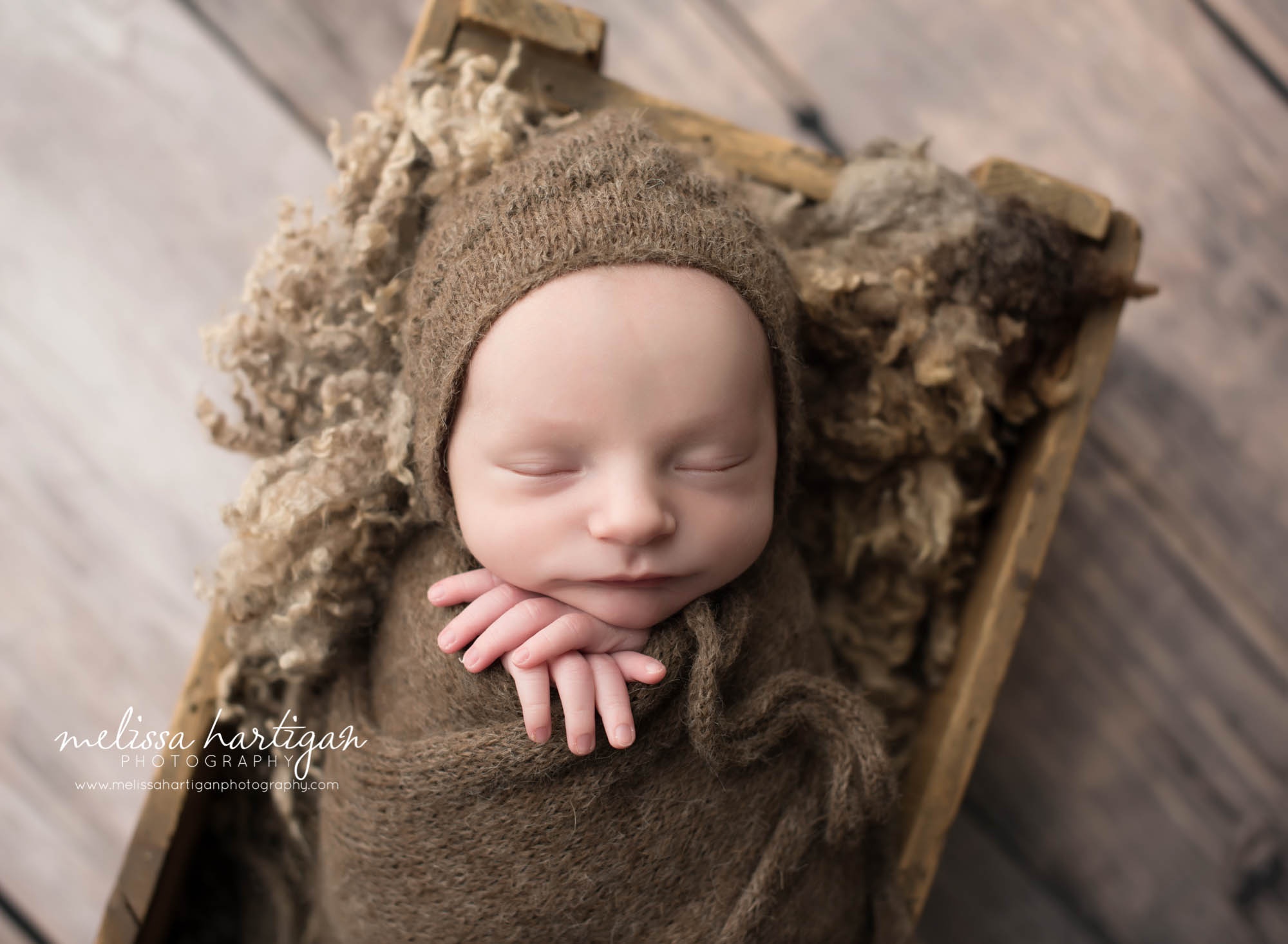 Melissa Hartigan Photography CT Newborn Photographer Stafford baby boy sleeping in wooden crate wrapped in brown blanket and matching knit hat with hands sticking out