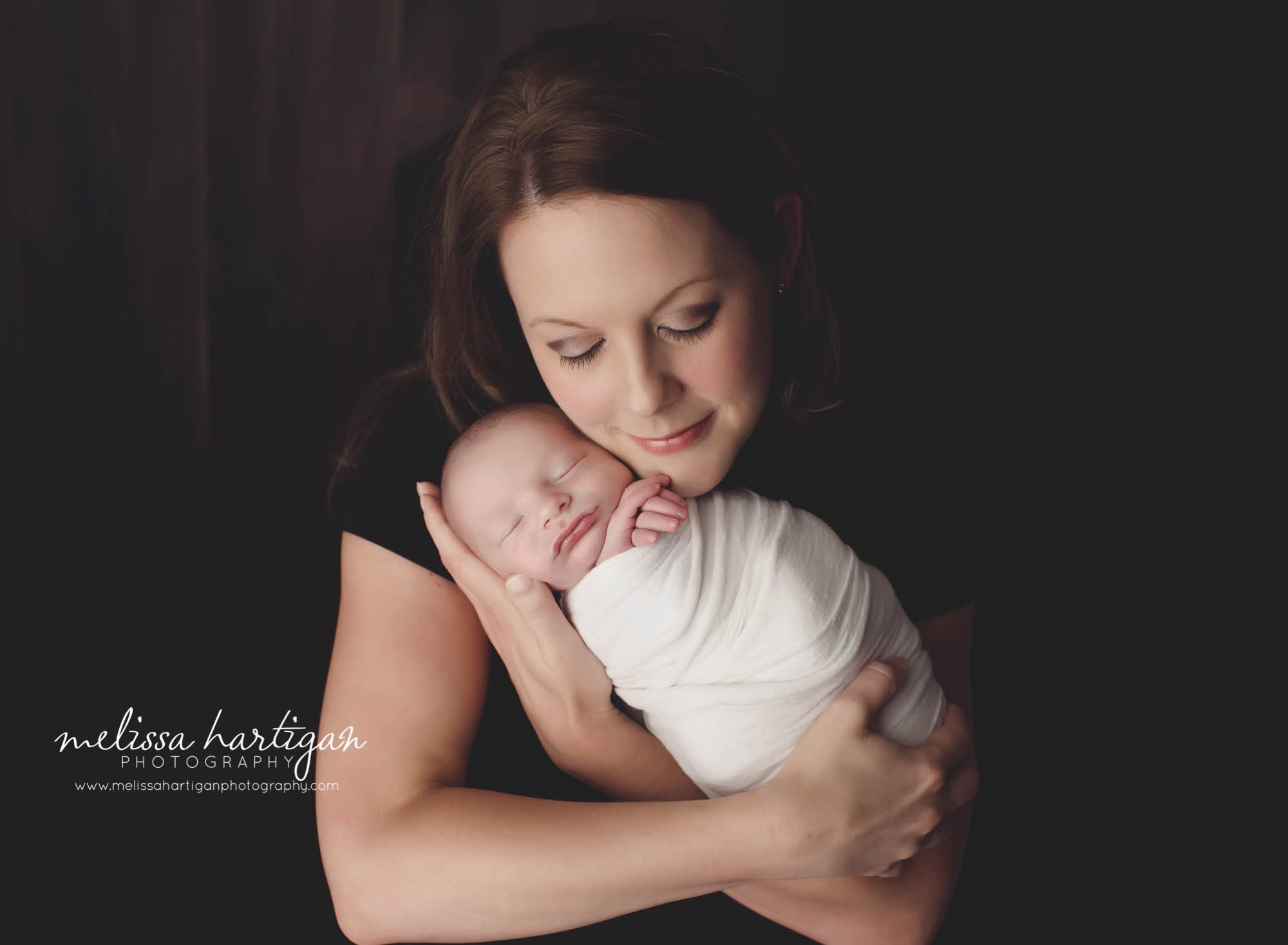 Melissa Hartigan Photography CT Newborn Photographer Stafford baby boy sleeping wrapped in cream held by mother close to face with eyes closed