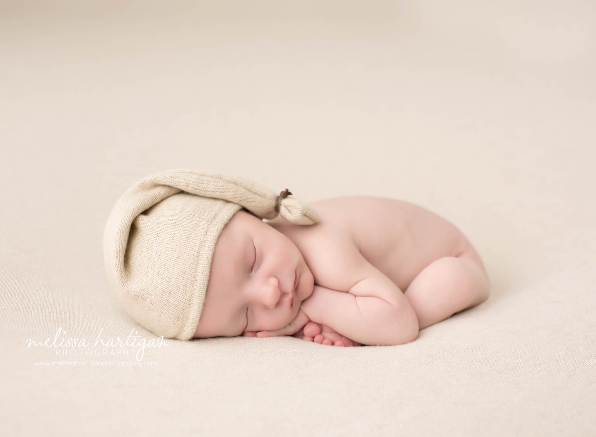 Melissa Hartigan Photography CT Newborn Photographer Stafford baby boy sleeping wearing cream knit hat on cream blanket