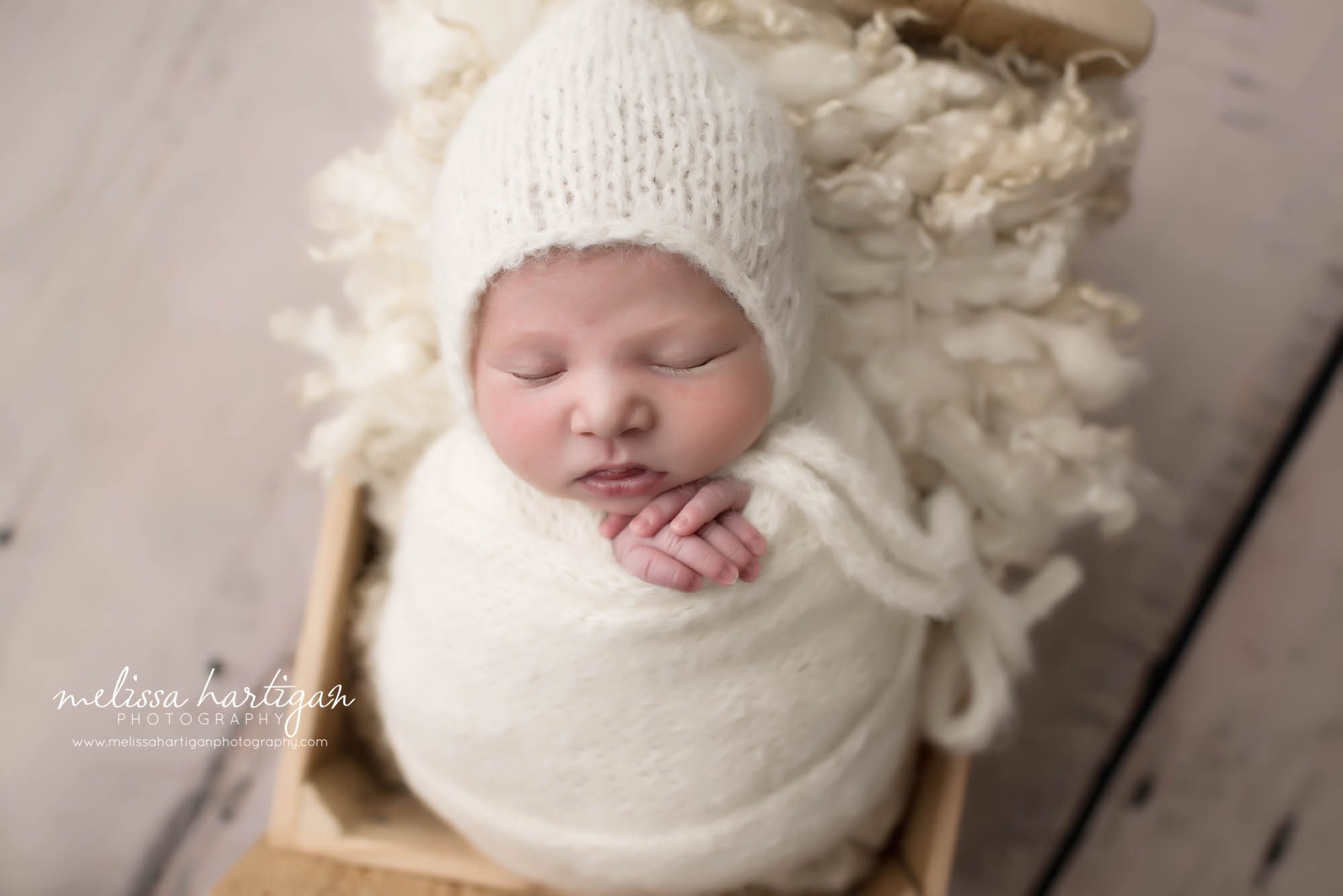 Melissa Hartigan Photography CT Newborn Photographer Ashford baby girl sleeping wrapped in cream with matching hat in wooden bed hands sticking out