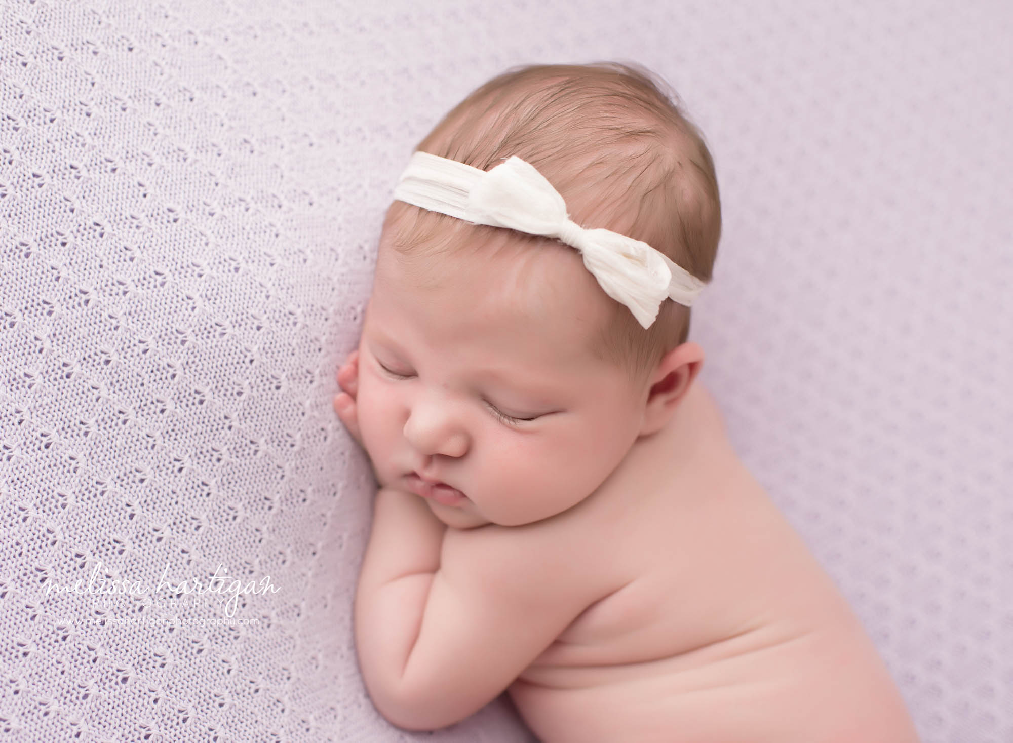 Melissa Hartigan Photography CT Newborn Photographer Ashford baby girl sleeping wearing cream bow headband laying on light purple blanket