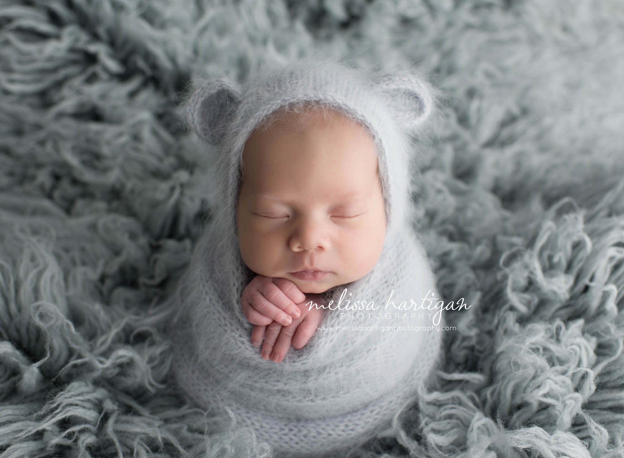 Melissa Hartigan Photography CT Newborn Photographer Taave CT Newborn Session baby boy sleeping wearing light blue snit hat with ears and matching wrap with hands sticking out