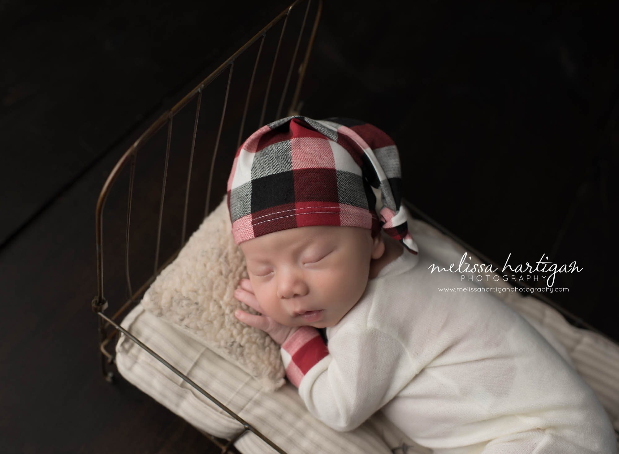 Melissa Hartigan Photography CT Newborn Photographer Taave CT Newborn Session baby boy wearing red plaid outfit and hat sleeping in little metal bed