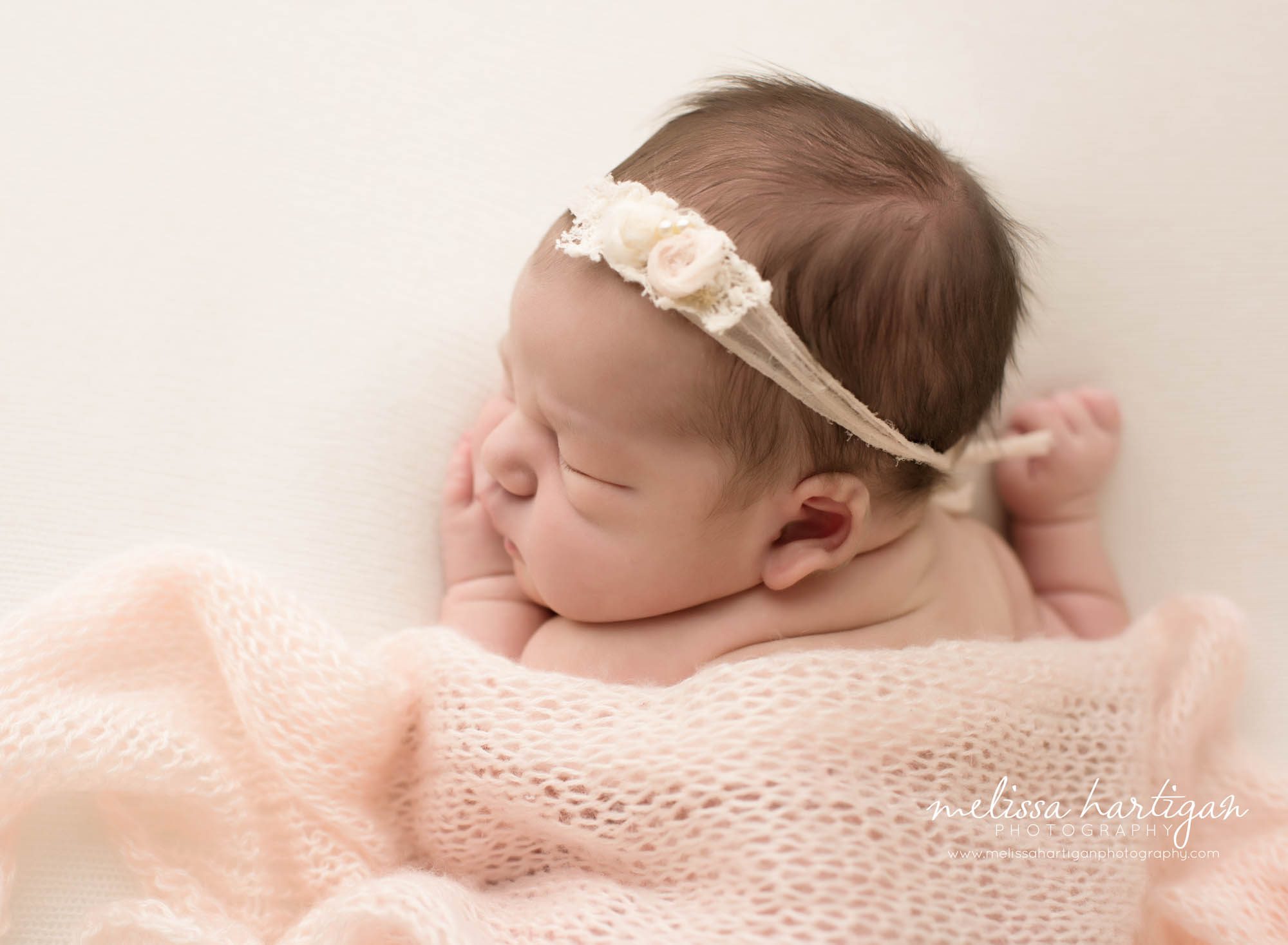 Melissa Hartigan Photography CT Newborn Photographer Emerson CT Newborn Session baby girl sleeping under soft pink knit blanket wearing place pink floral headband