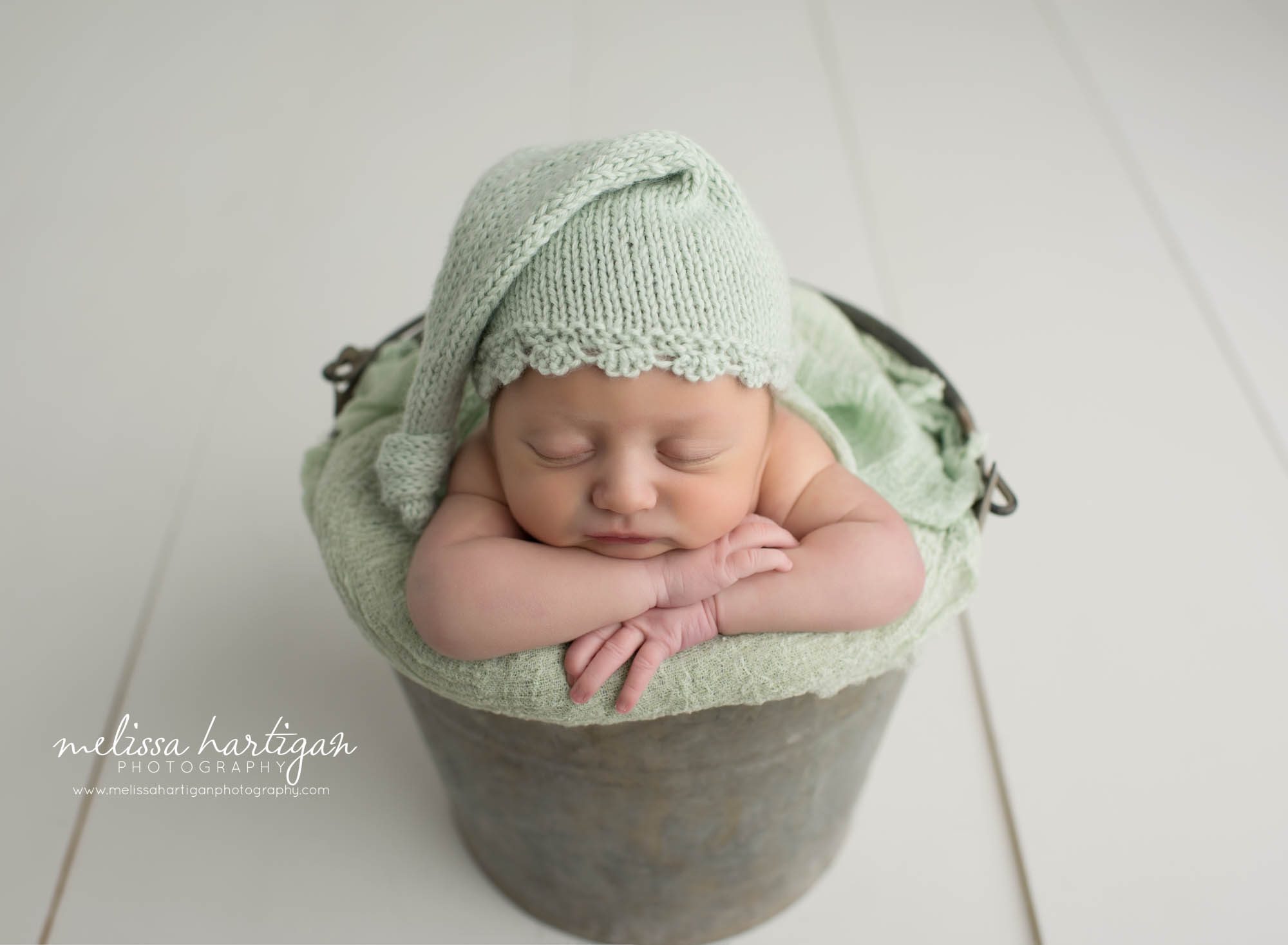 Leila CT Newborn Session baby girl sleeping in metal bucket with green blanket and hat