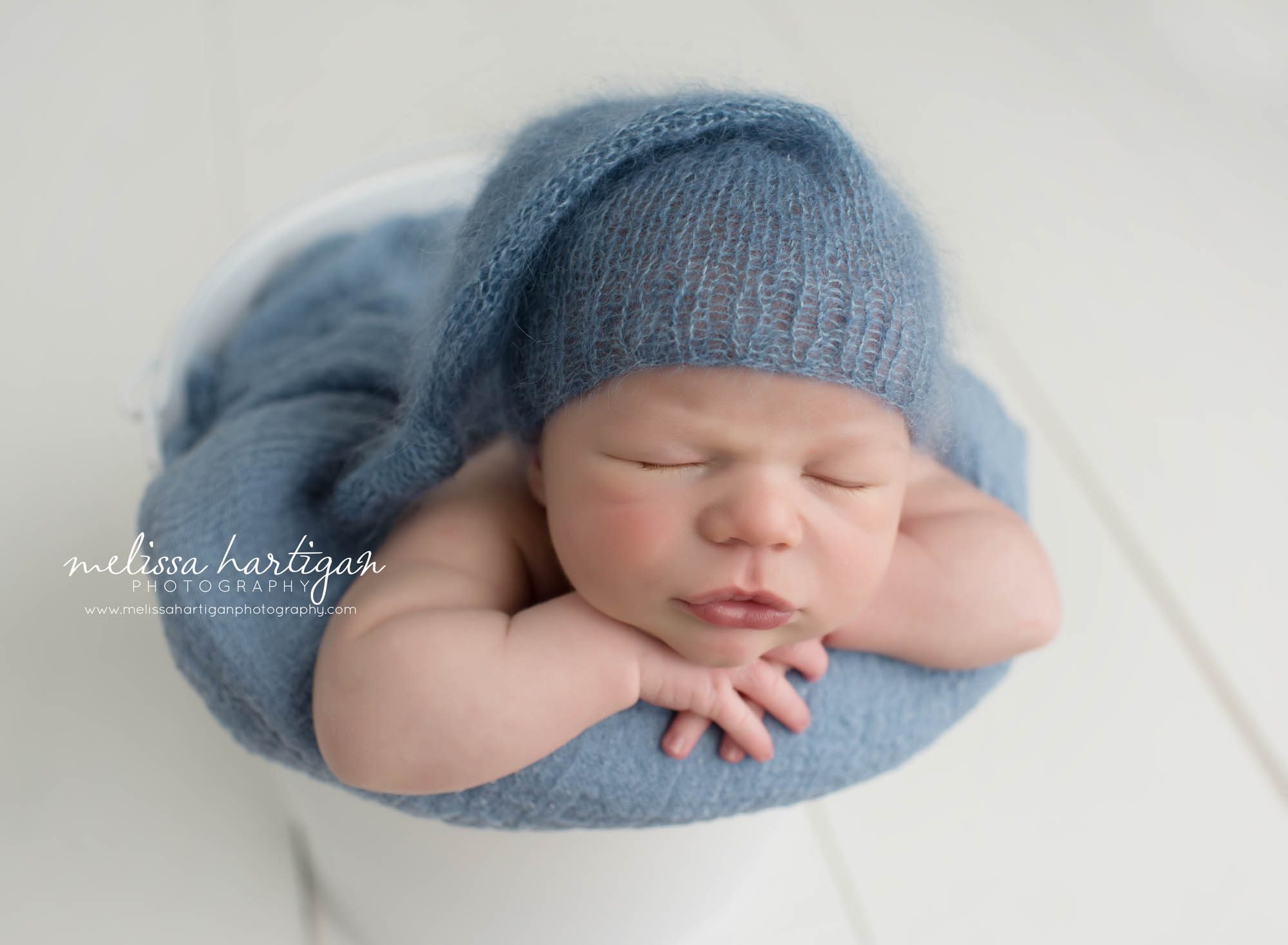 Newborn Session CT baby boy sleeping in white bucket with blue blanket and hat