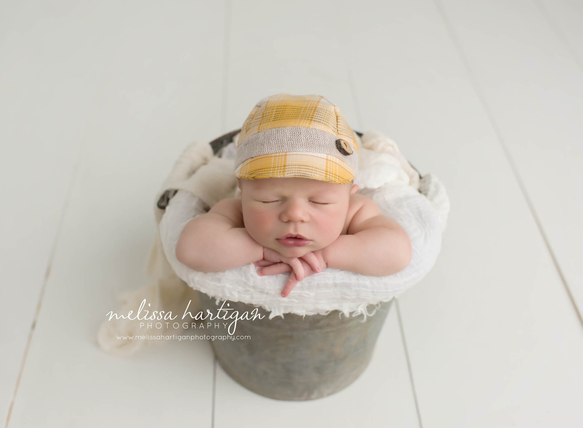 Newborn Session CT baby boy sleeping in metal bucket with plaid hat