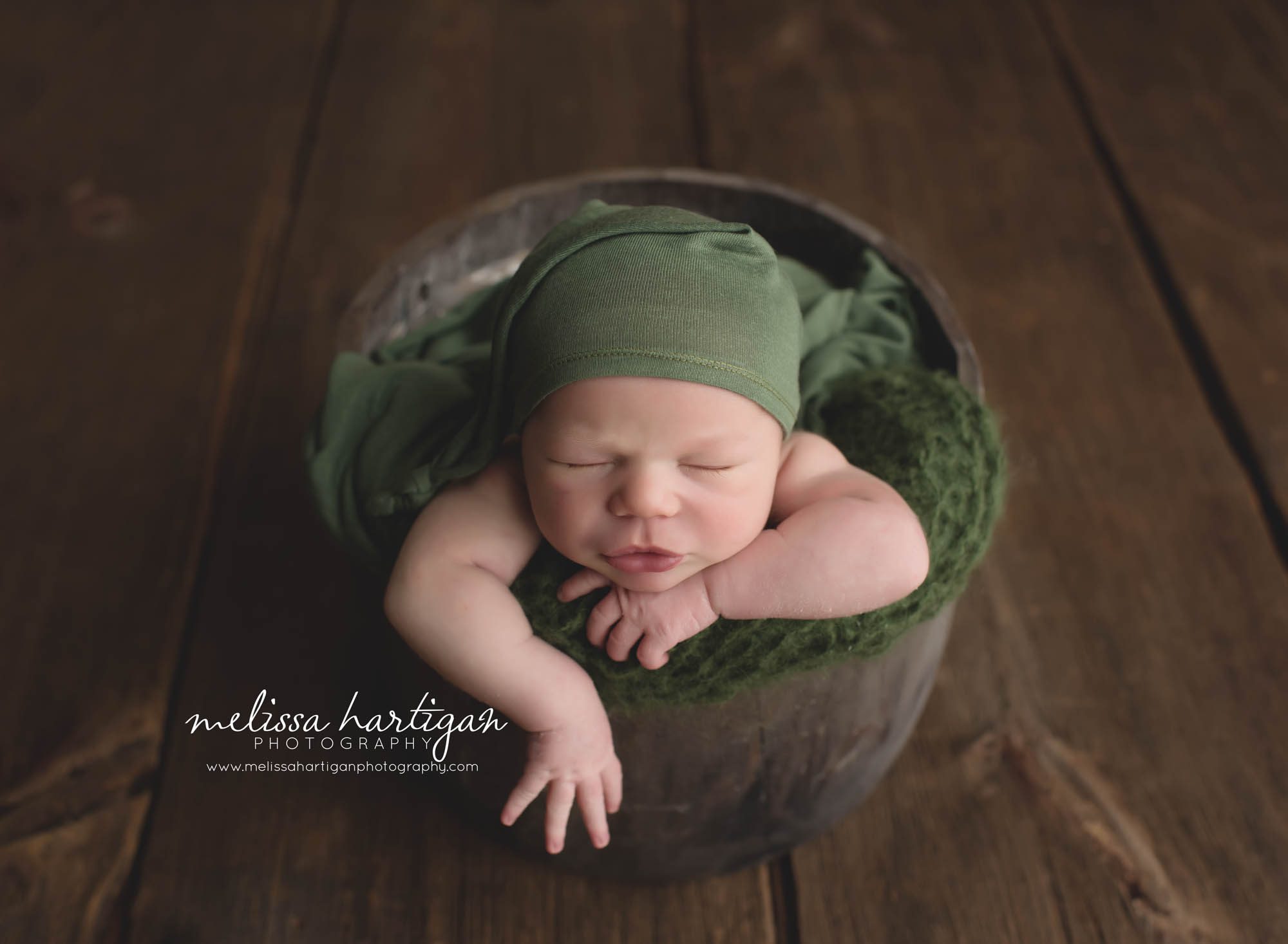 Newborn Session CT baby boy sleeping in wooden bucket with green blanket and hat