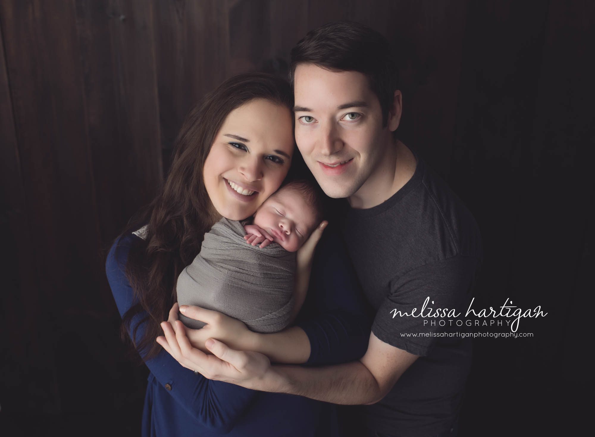 CT Newborn Photographer baby boy sleeping wrapped in gray held by parents
