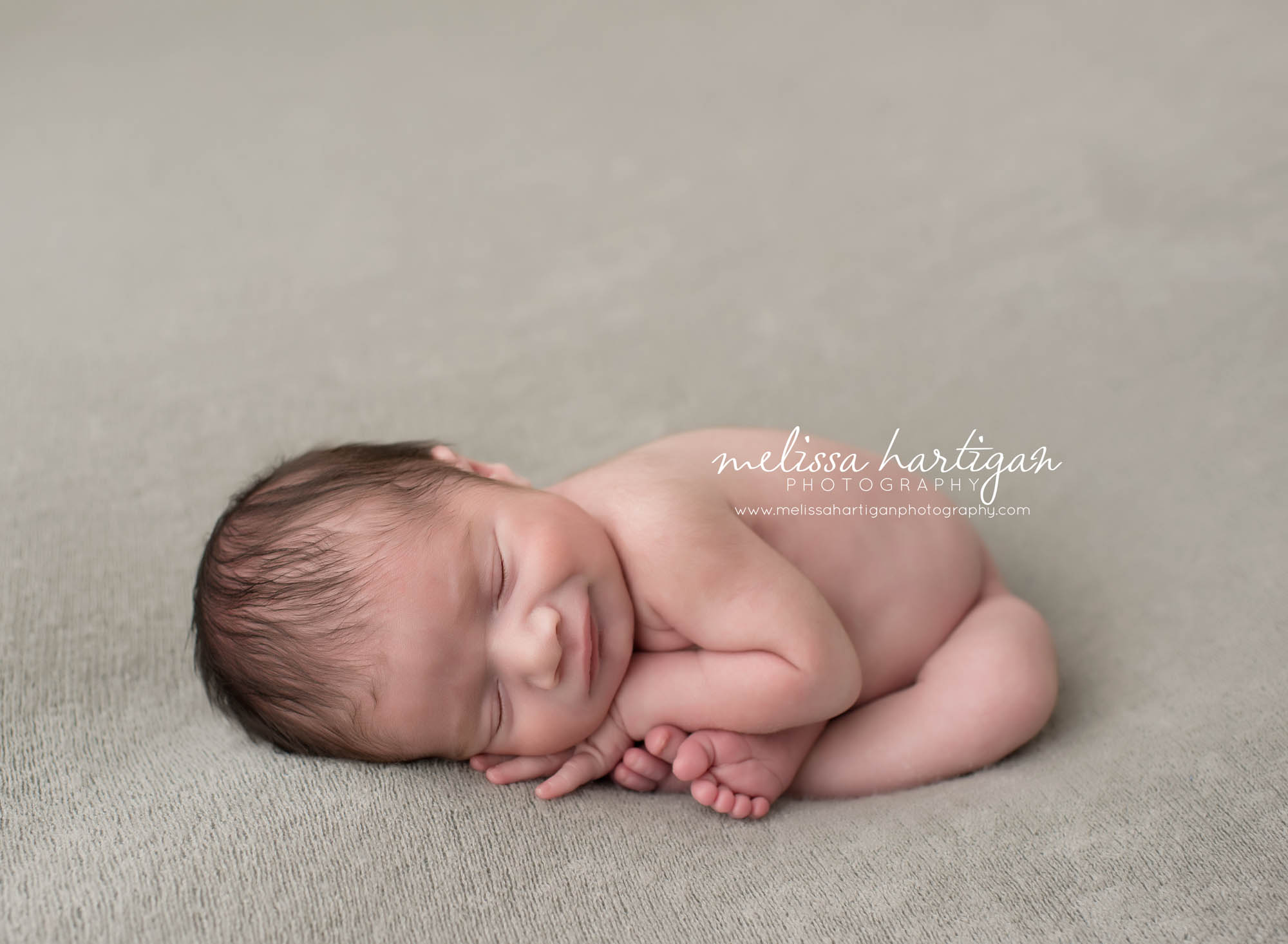 CT Newborn Photographer baby boy sleeping on gray blanket smiling