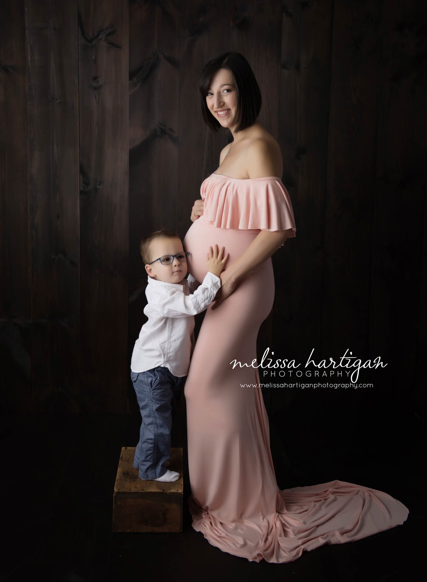 CT Maternity Photographer maternity pose mom cradling baby bump with son listening on belly
