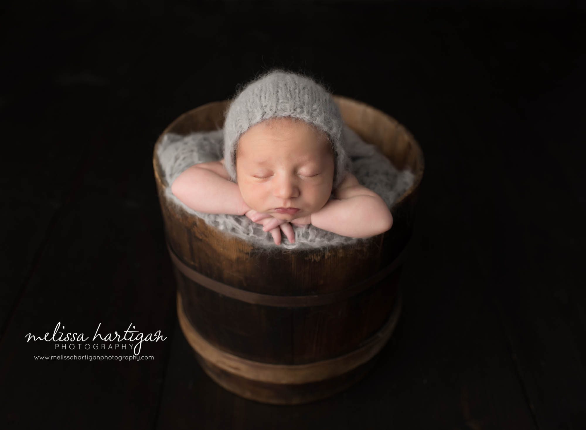 Newborn Photographer Connecticut newborn pose baby sleeping in wooden bucket with gray knit hat