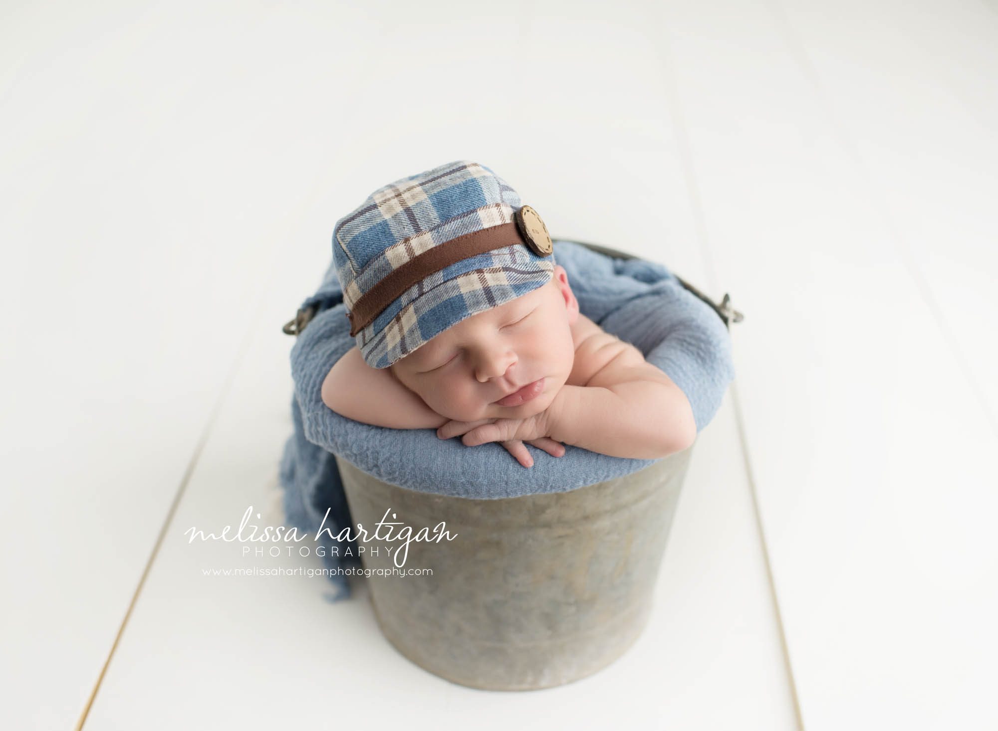 CT Baby Photography newborn boy sleeping in metal bucket with blue blanket and plaid hat