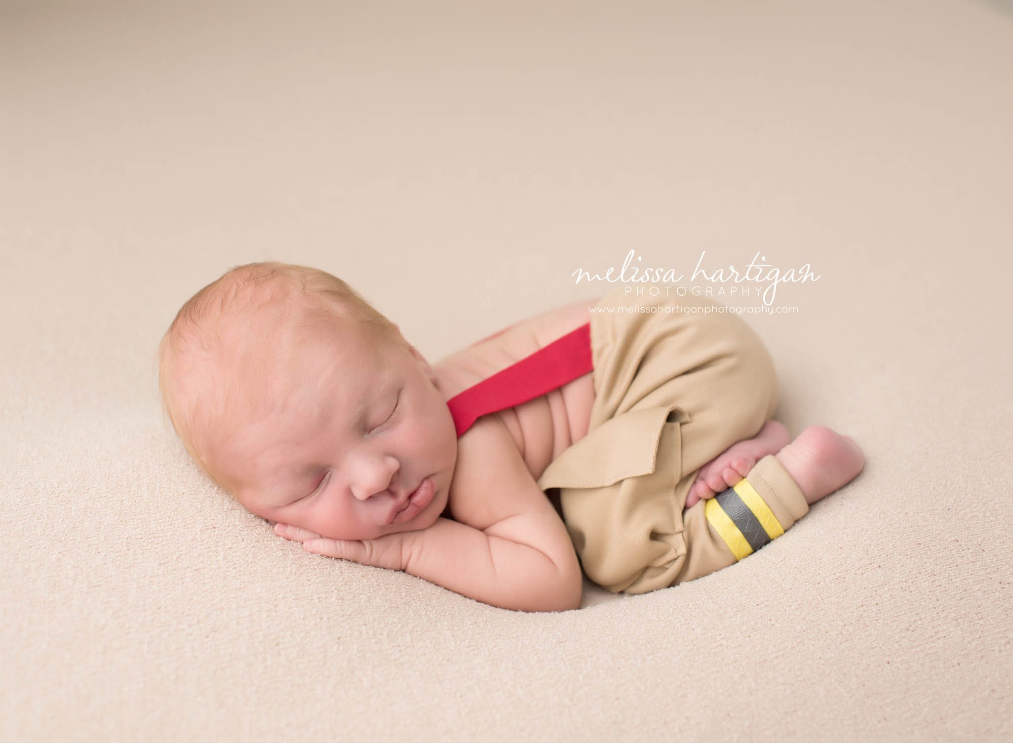 newborn boy in fireman outfit sleeping