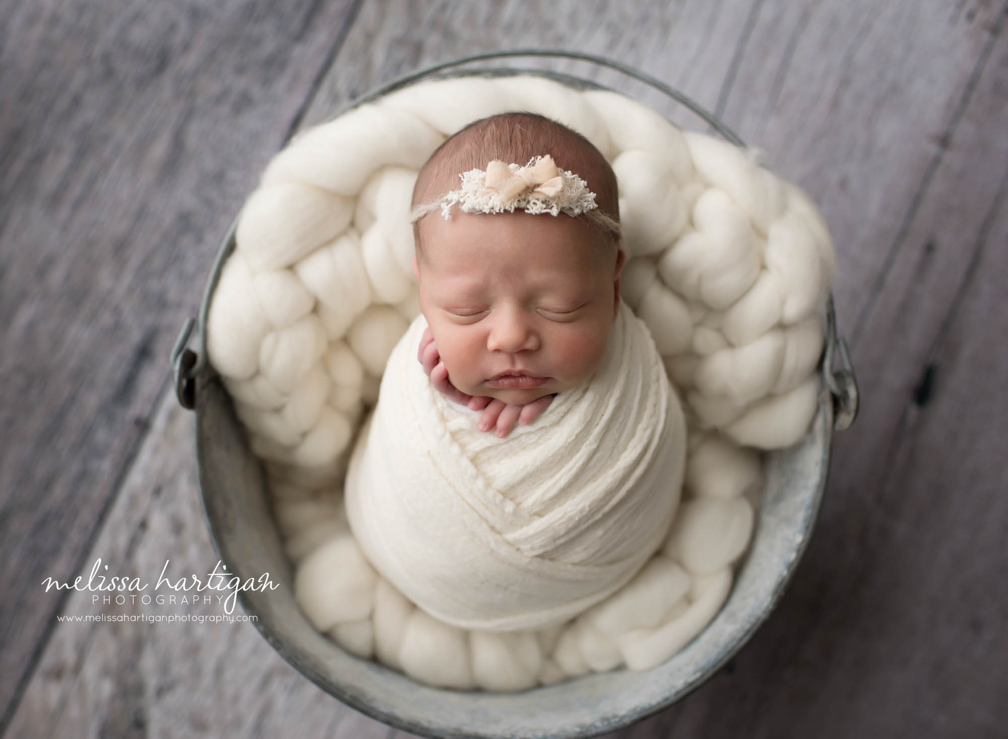 Baby girl wrapped in cream wrap placed in bucket