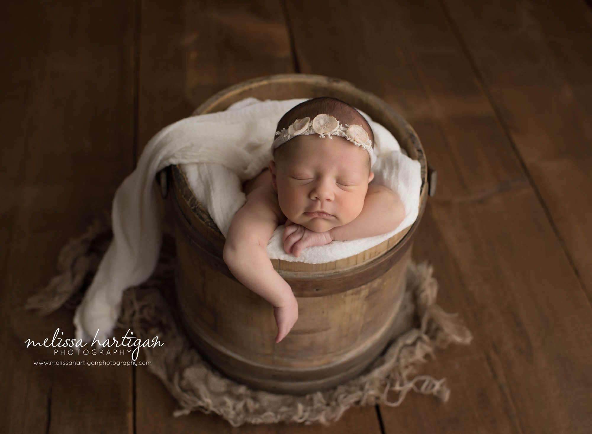 baby girl posed in rustic bucket with cream fabric draped over rustic newborn photos professional newborn photography in CT