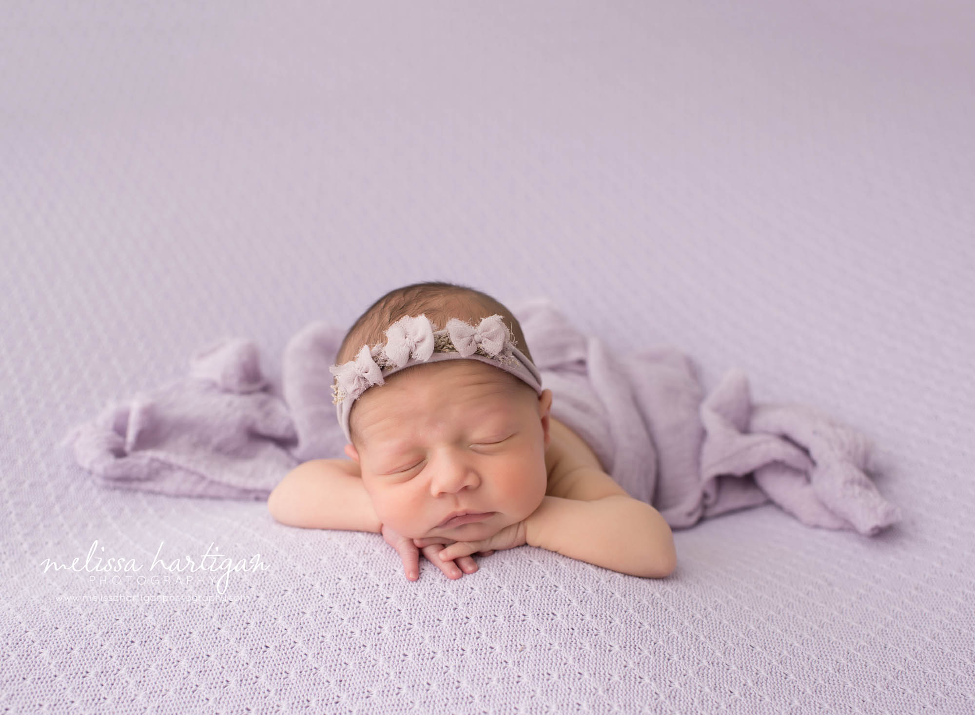 newborn baby posed on light lavendar colored blanket with light purple wrap draped over her maternity and newborn photographer in CT