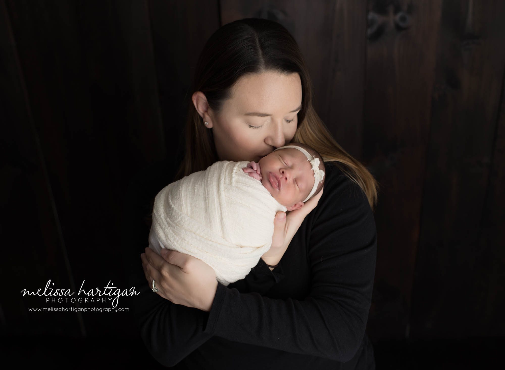mom osed with newborn baby girl holding her close giving her baby a kiss moms love