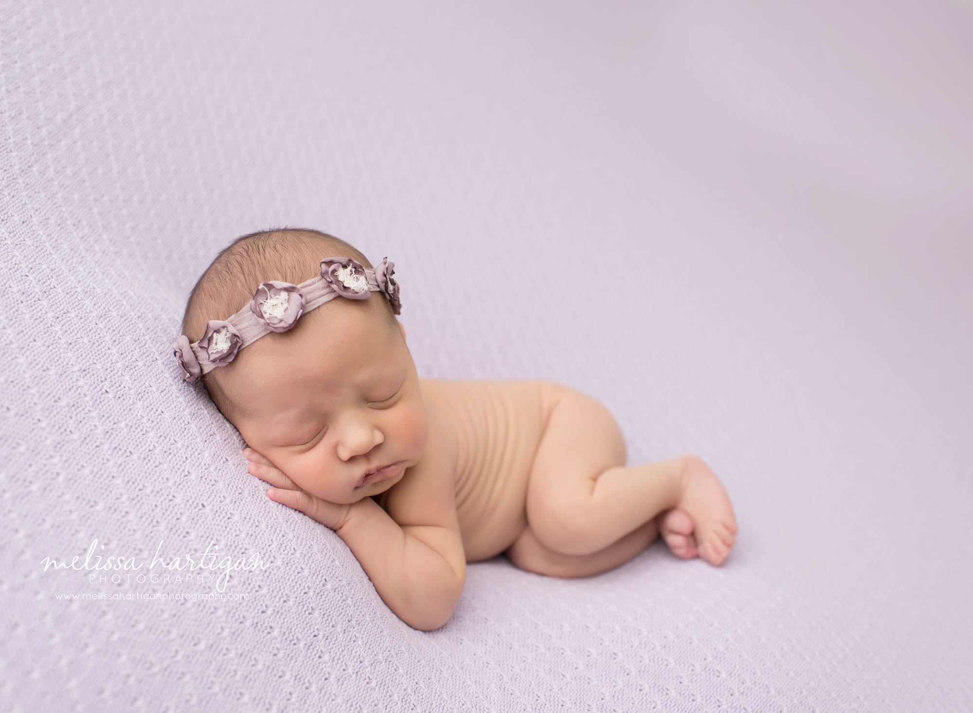 Baby girl laying on textured lavender blanket wearing muted mauve baby girl headband tieback CT baby photos